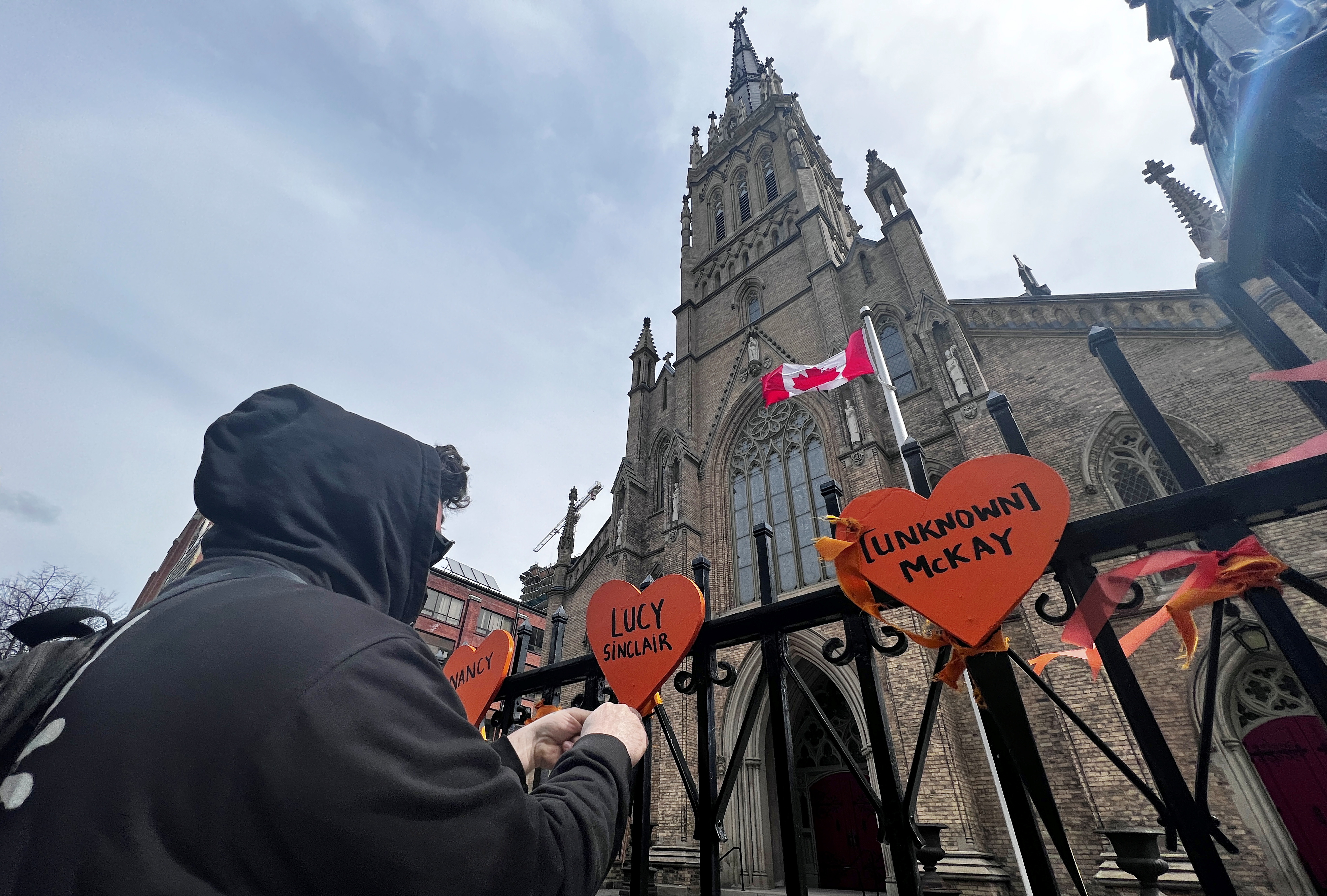 A protester fixes hearts to a gate outside a Toronto church in honour of victims of residential schools