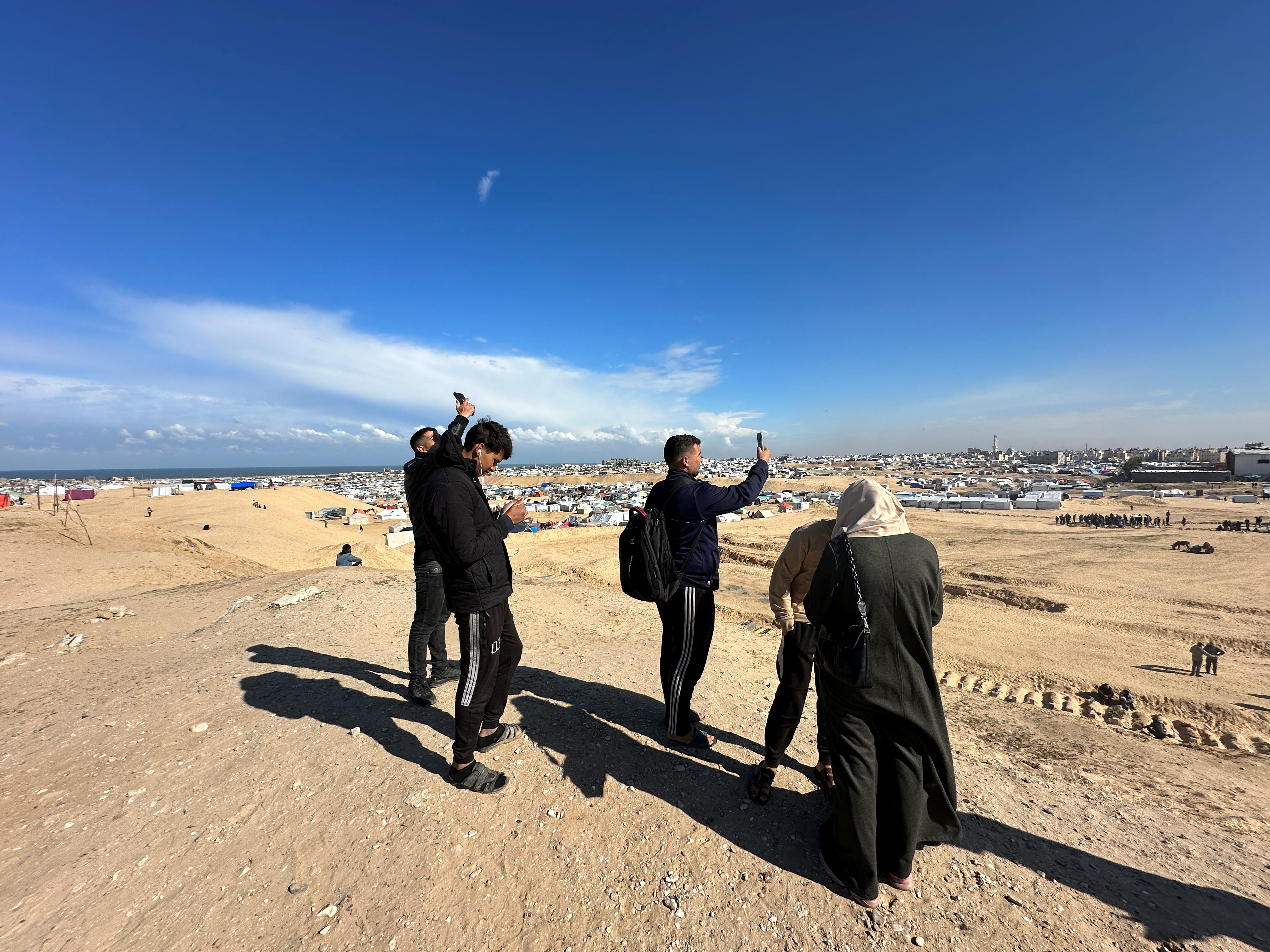 Displaced Palestinians try to get internet service on their phones through the Egyptian networks to communicate with their relatives, near the border in Rafah in the southern Gaza Strip