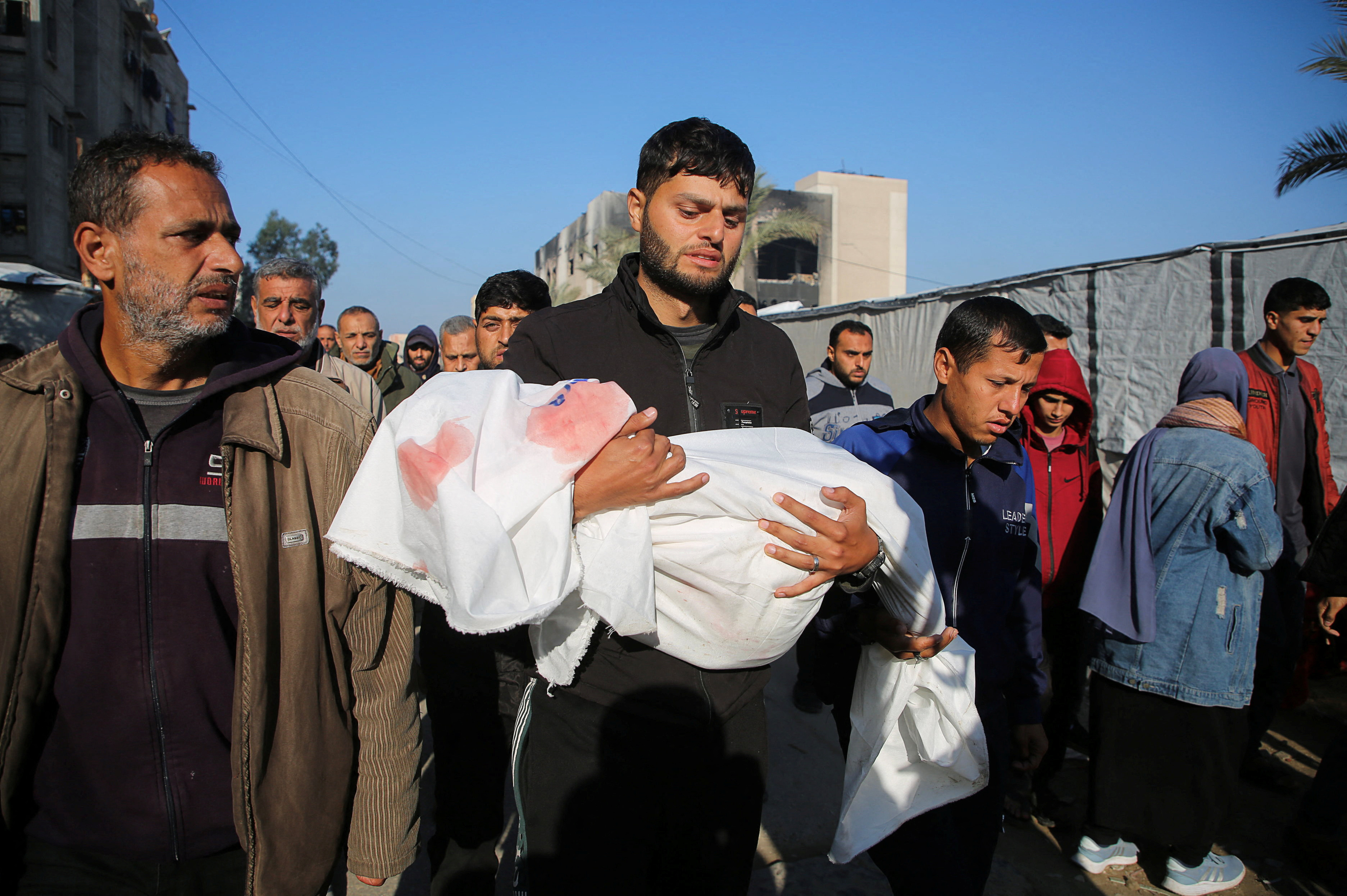 A mourner carries the body of a Palestinian child killed in Israeli air raids, before a ceasefire between Hamas and Israel takes effect.