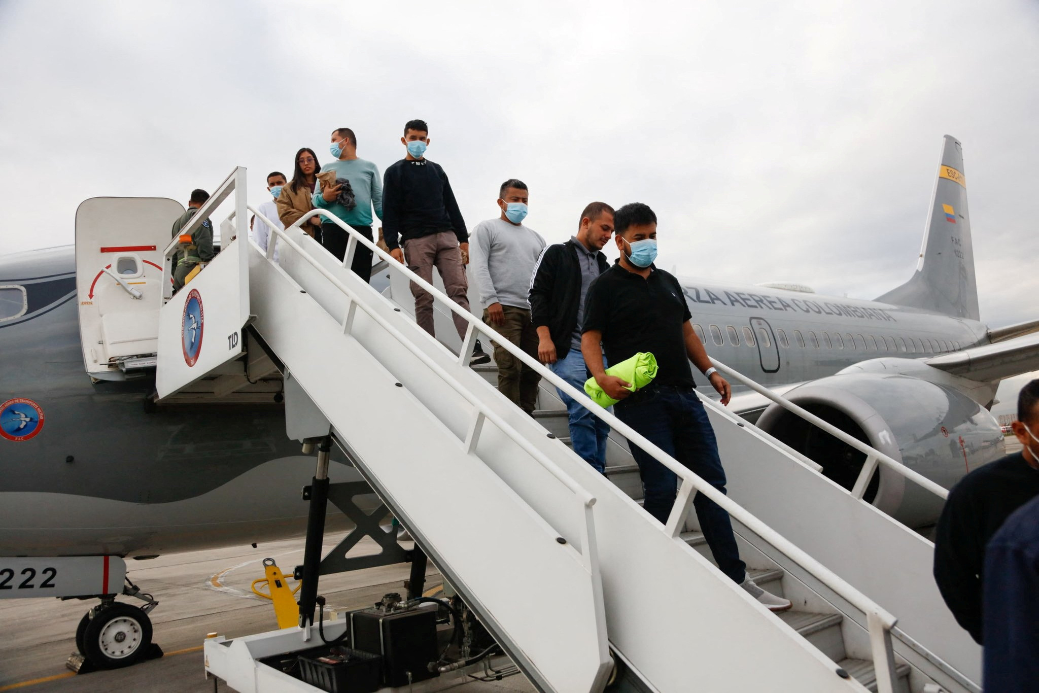 Migrants walk down the staircase of a plane carrying out a deportation flight.