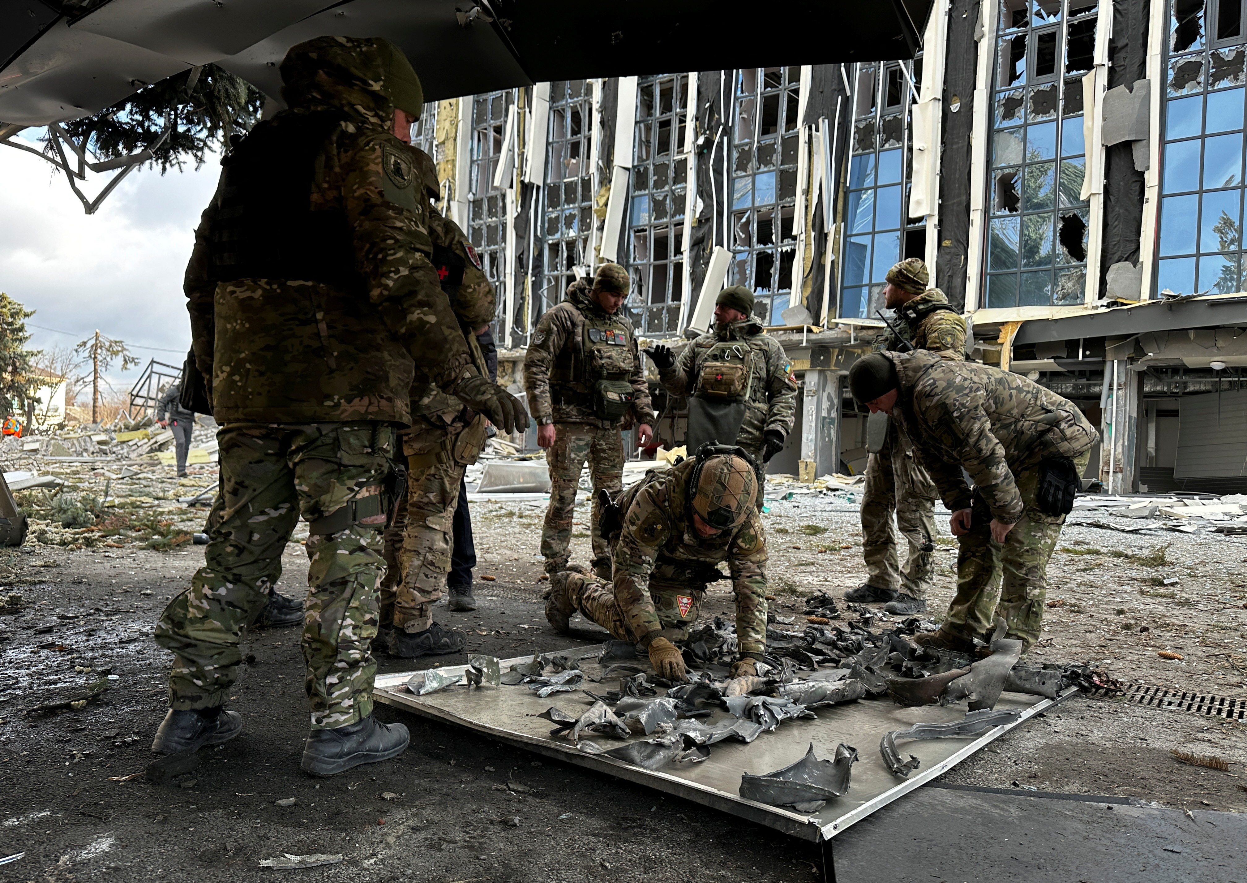 Police bomb squad members work at a site of a building hit by a Russian missile strike in Izium, Ukraine