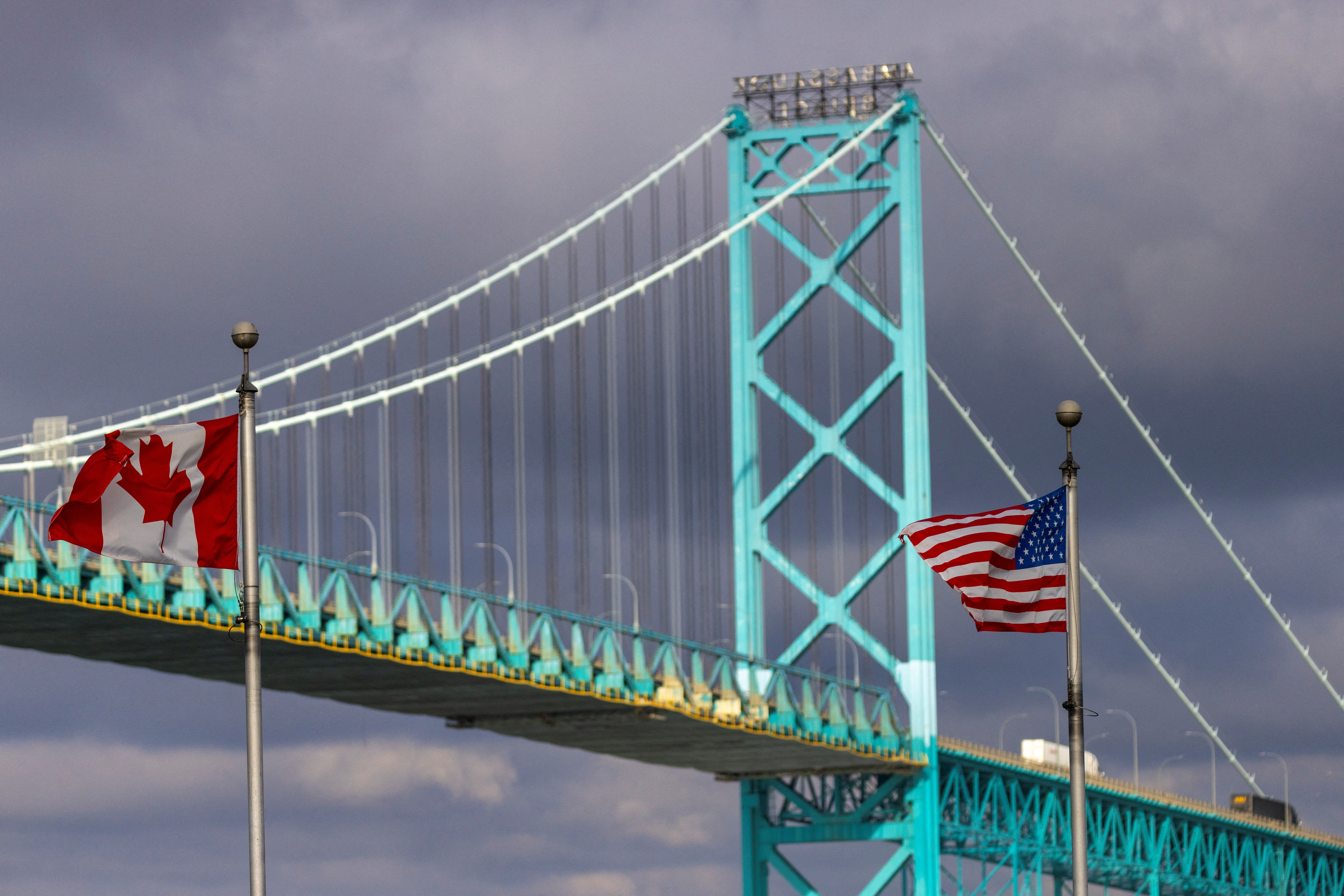 Flags wave in the wind near the Ambassador Bridge which connects Windsor, Ontario, Canada, and Detroit, Michigan, U.S., in Windsor, Ontario, Canada February 4, 2025. REUTERS/Carlos Osorio