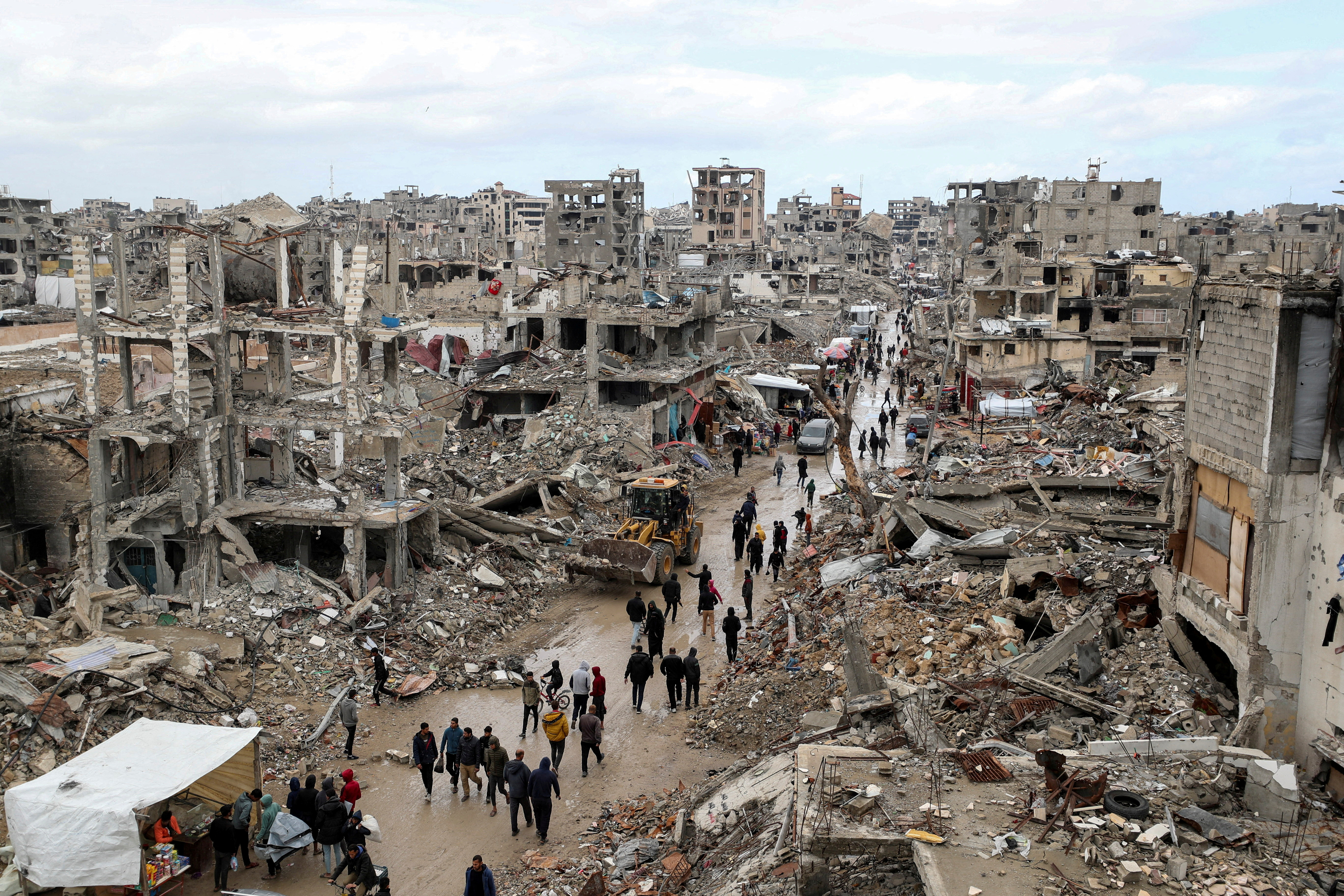 FILE PHOTO: Palestinians walk past the rubble of buildings destroyed during the Israeli offensive, on a rainy day, amid a ceasefire between Israel and Hamas, in Gaza City February 6, 2025. REUTERS/Dawoud Abu Alkas/File Photo