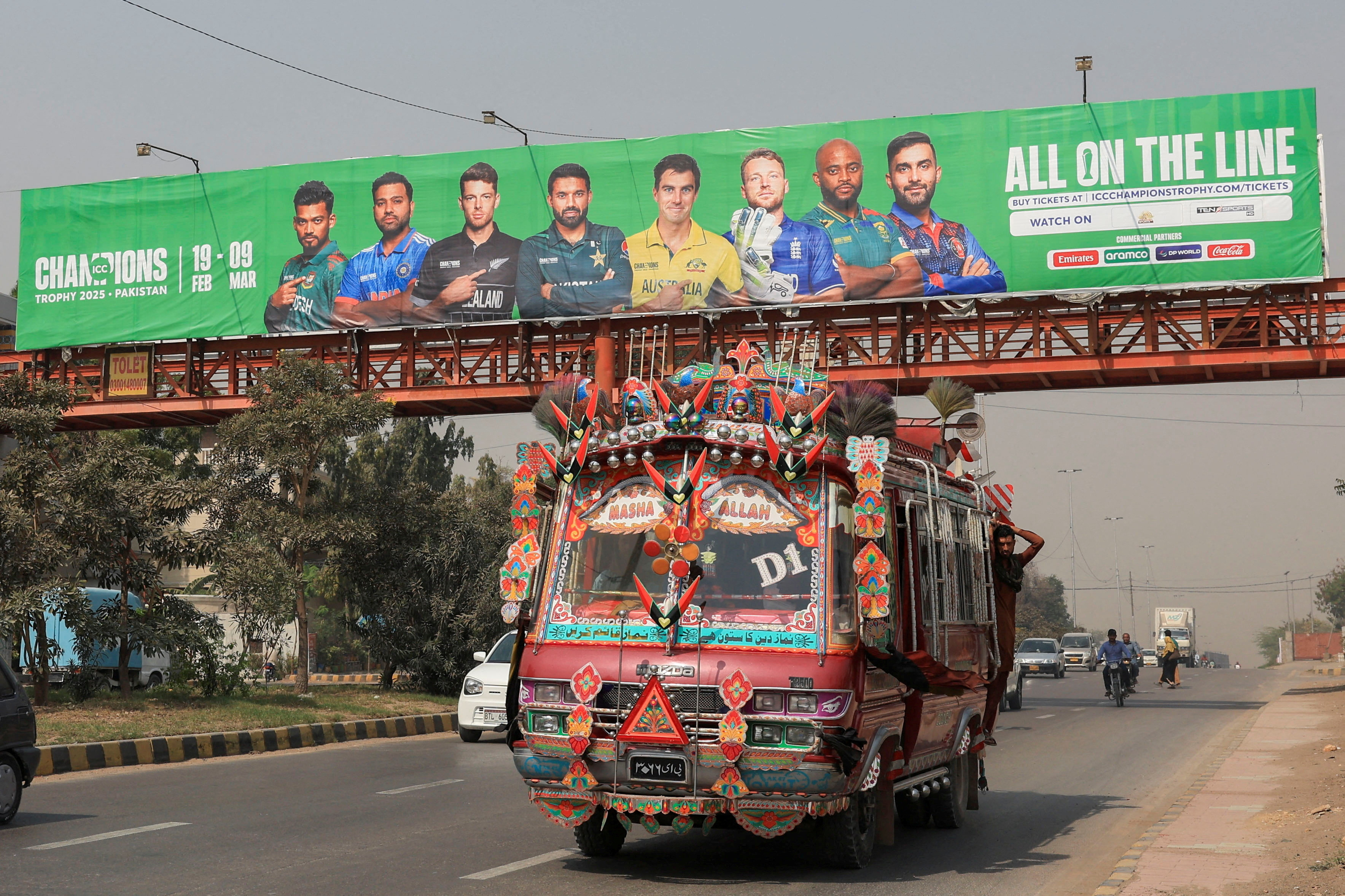 FILE PHOTO: A decorated van drives past under a pedestrian bridge with an advertisment banner, ahead of the ICC Champions Trophy 2025 tournament, in Karachi, Pakistan February 13, 2025. REUTERS/Akhtar Soomro/File Photo
