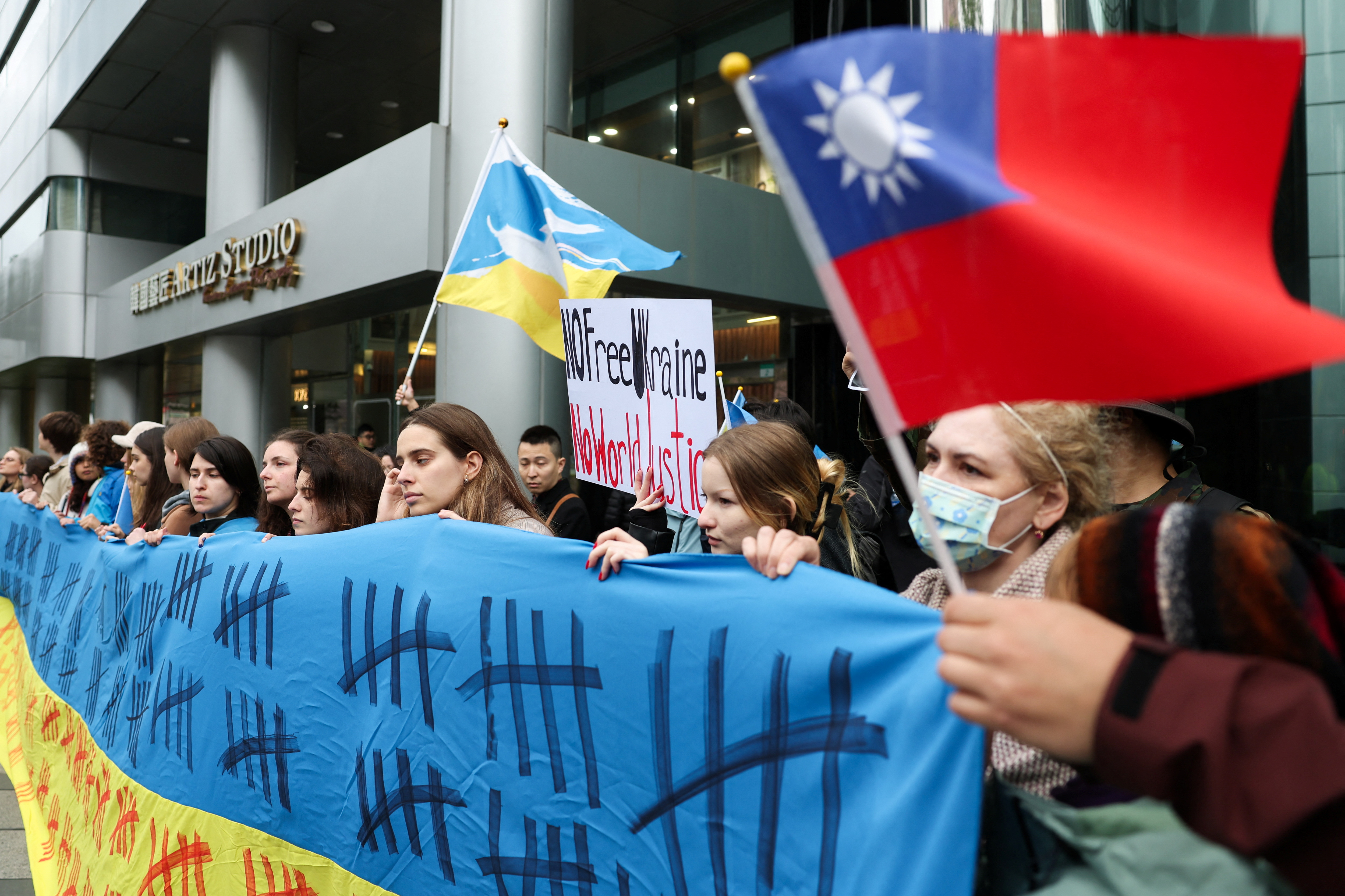 People hold a Ukrainian flag and a Taiwan flag during a protest to mark the third anniversary of Russia's invasion of Ukraine, in Taipei