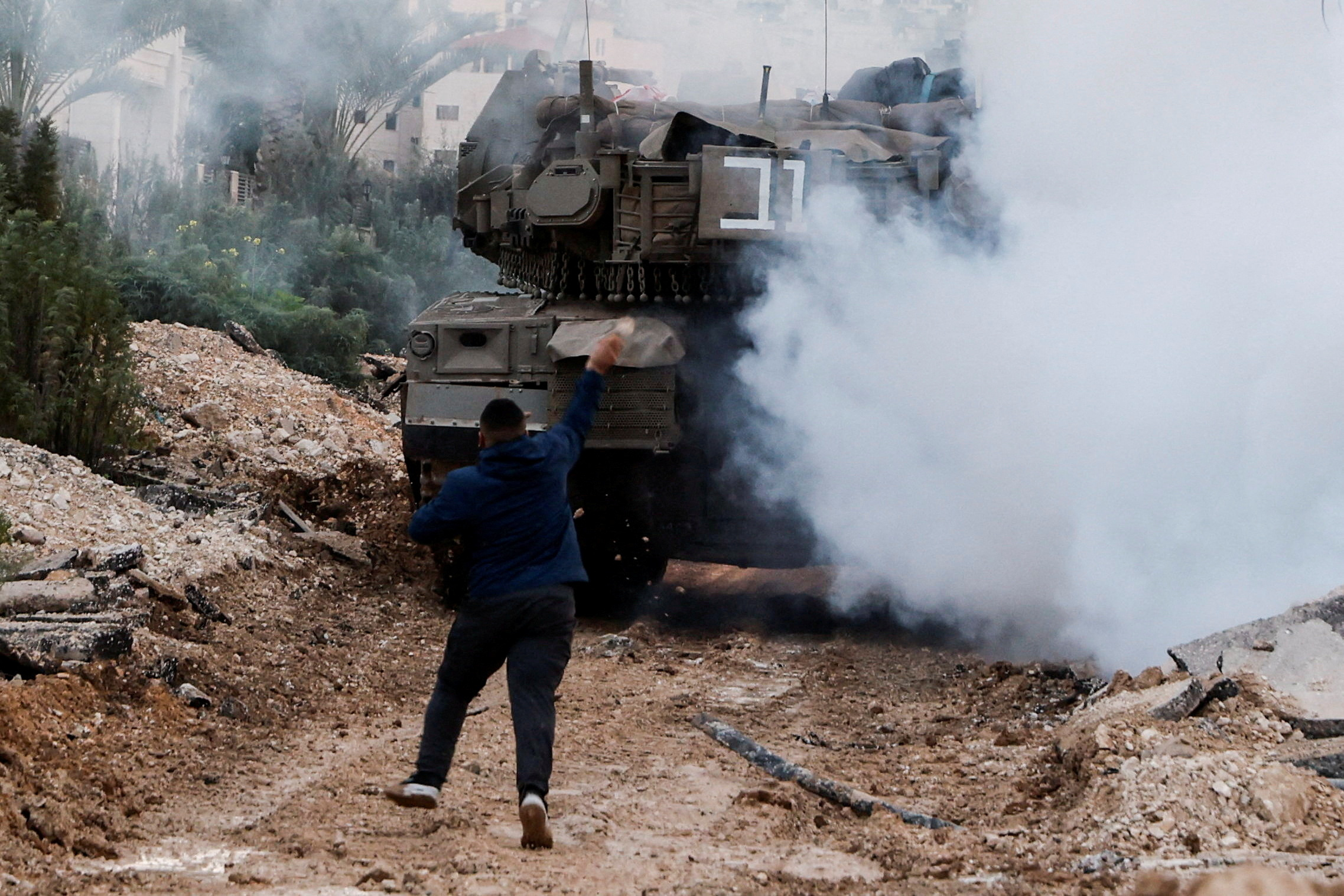 a man throws something at a tank surrounded by smoke
