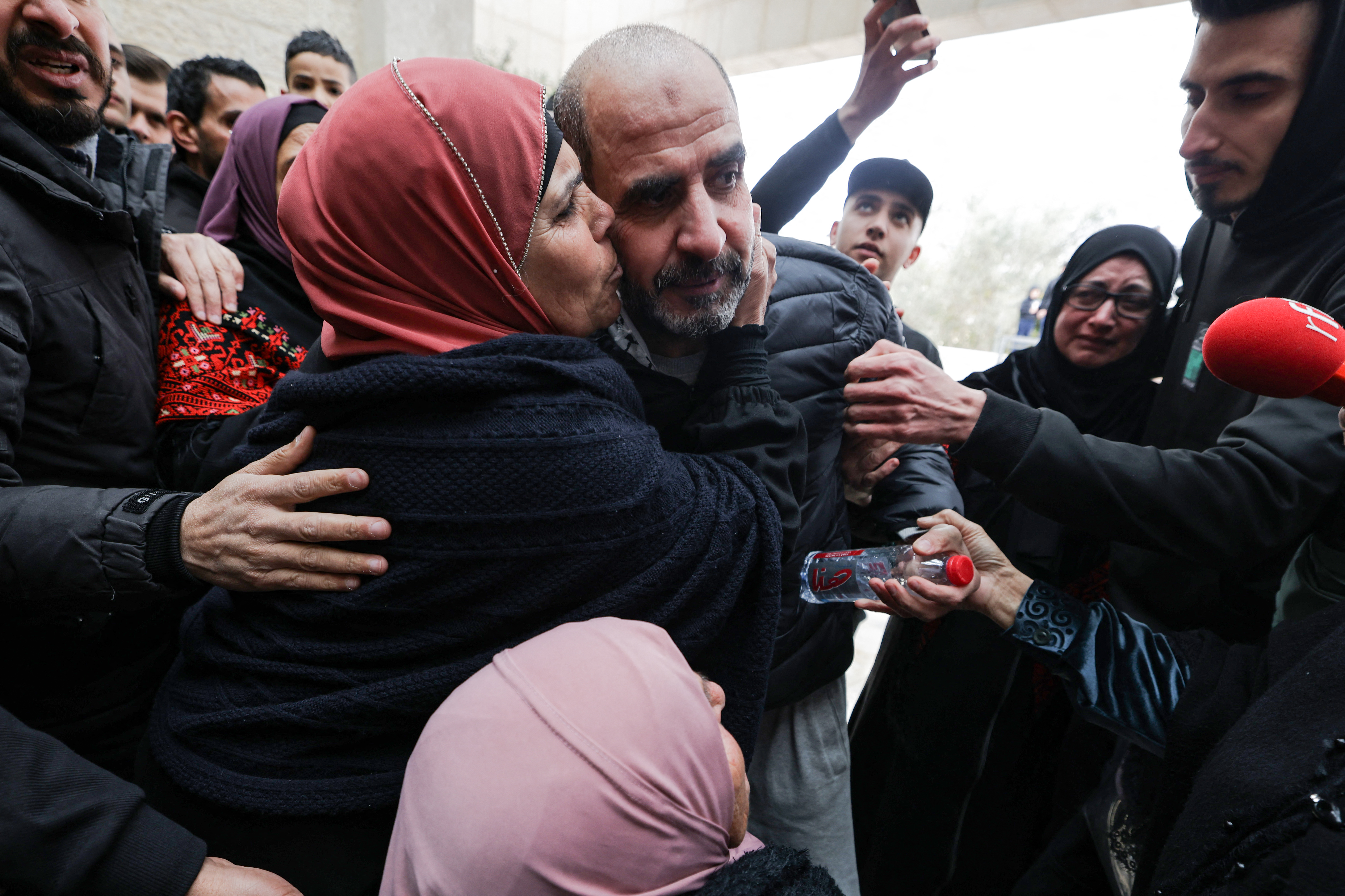 A former Palestinian prisoner is embraced by a family member after stepping out of a bus in the occupied West Bank city of Ramallah on February 8, 2025, as part of the fifth hostage-prisoner swap under a fragile Gaza truce. (Photo by JAAFAR ASHTIYEH / AFP)