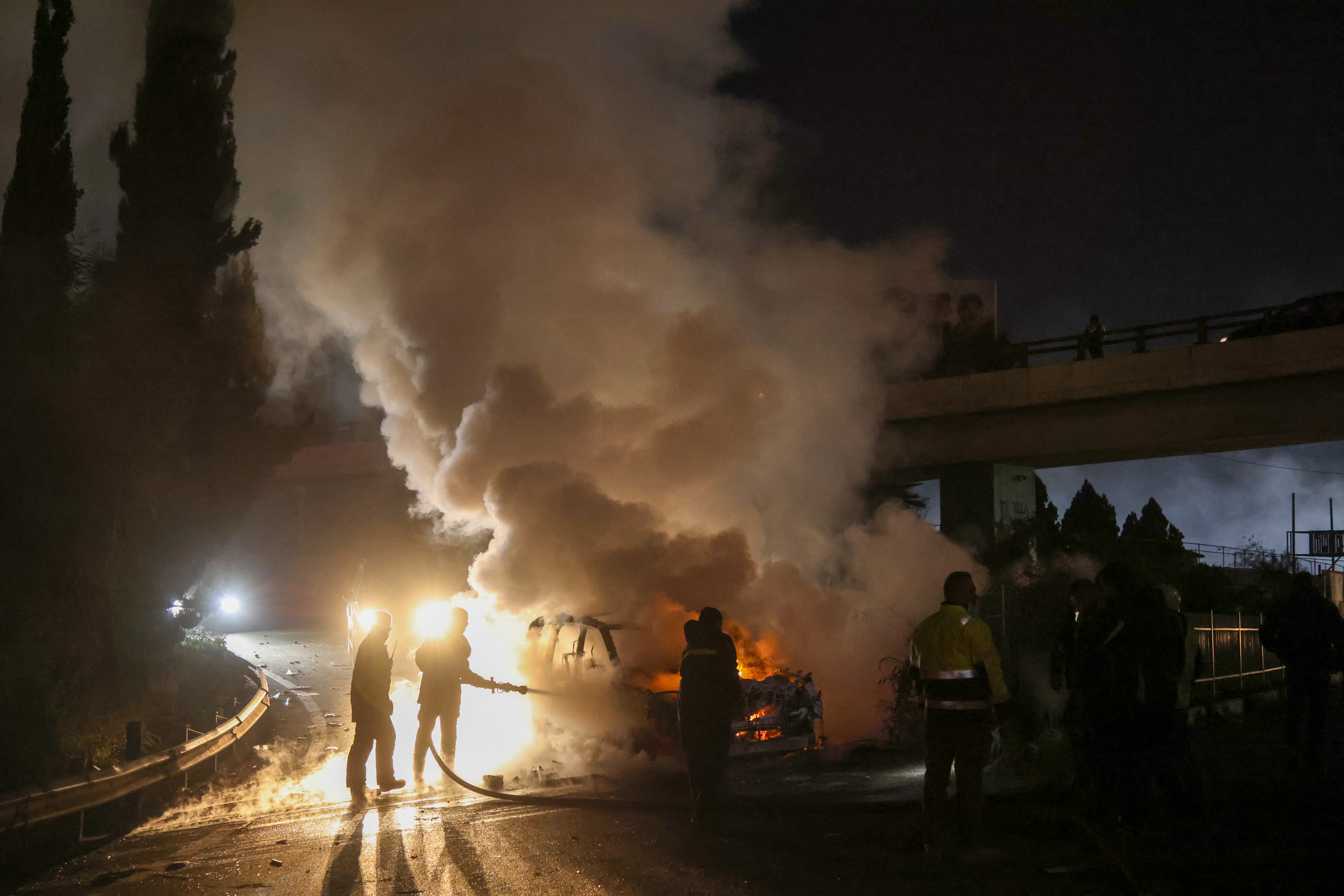 Firefighters extinguish a burning UNIFIL vehicle, set ablaze by protesters, on the road leading to Beiruts international airport on February 14, 2025. The Lebanese army pledged on February 14, to take firm action against those behind the torching of a UN peacekeeping vehicle on the Beirut airport road which had been cut by Hezbollah supporters for a second evening.