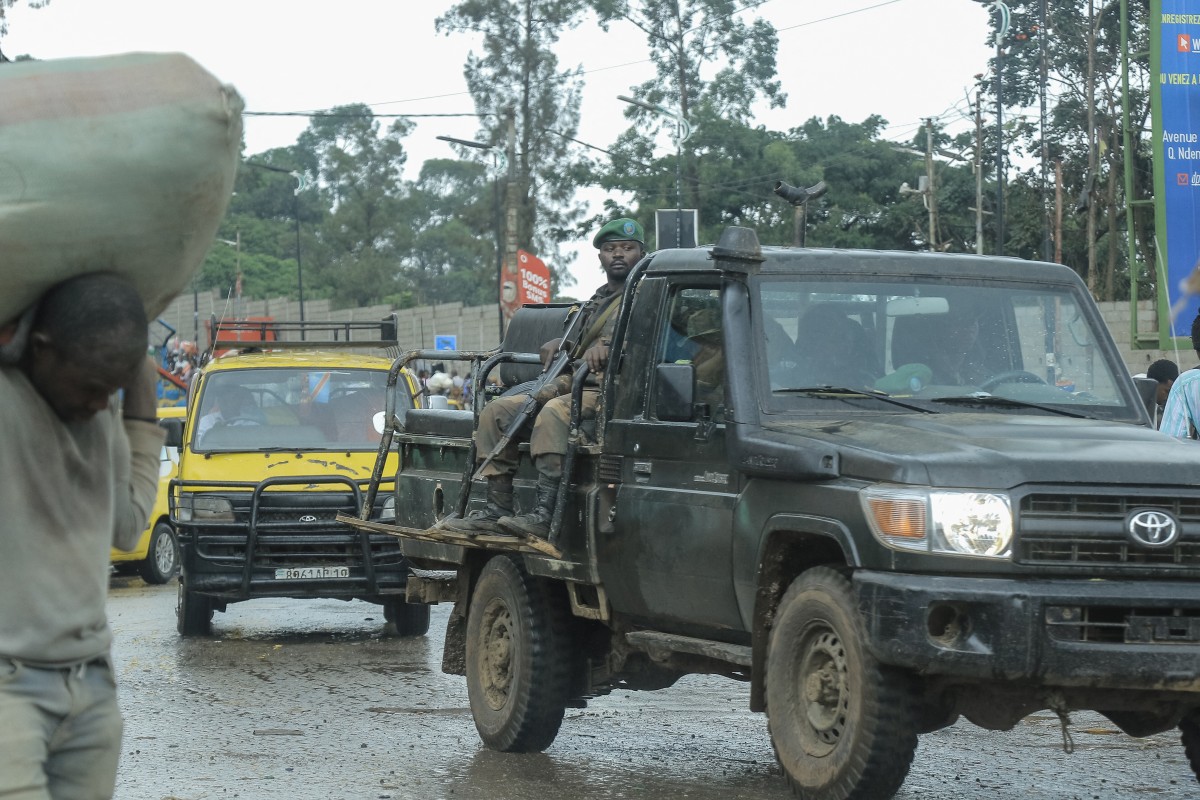 A soldier of the Armed Forces of the Democratic Republic of the Congo sits on the back of a pick-up truck.