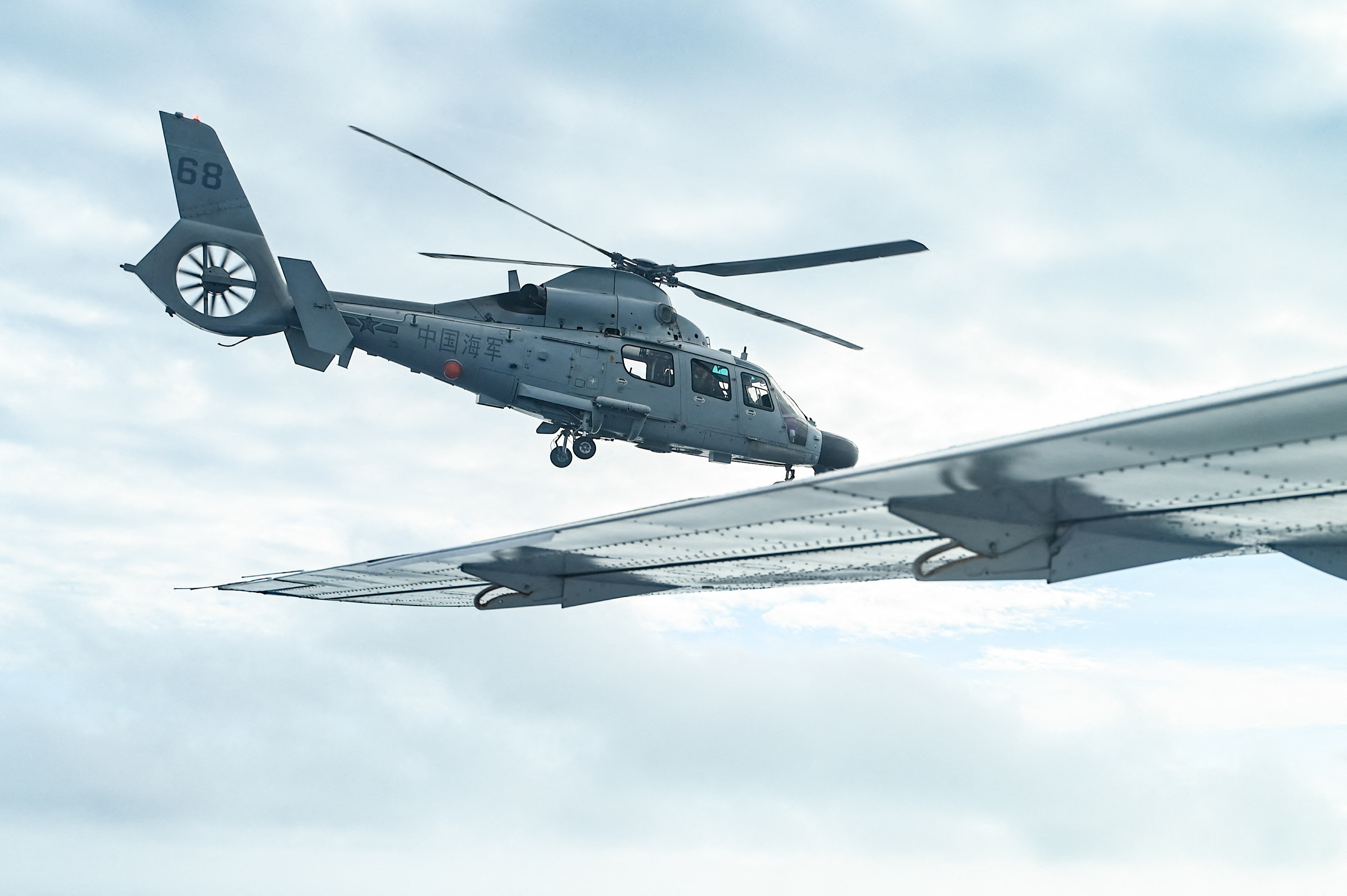 An aircraft identified by the Philippine Coast Guard as Chinese Navy helicopter (L) flies near the Bureau of Fisheries and Aquatic Resources (BFAR) plane during an aerial reconnaissance flight at Scarborough Shoal in the South China Sea on February 18, 2025. (Photo by Jam STA ROSA / AFP)