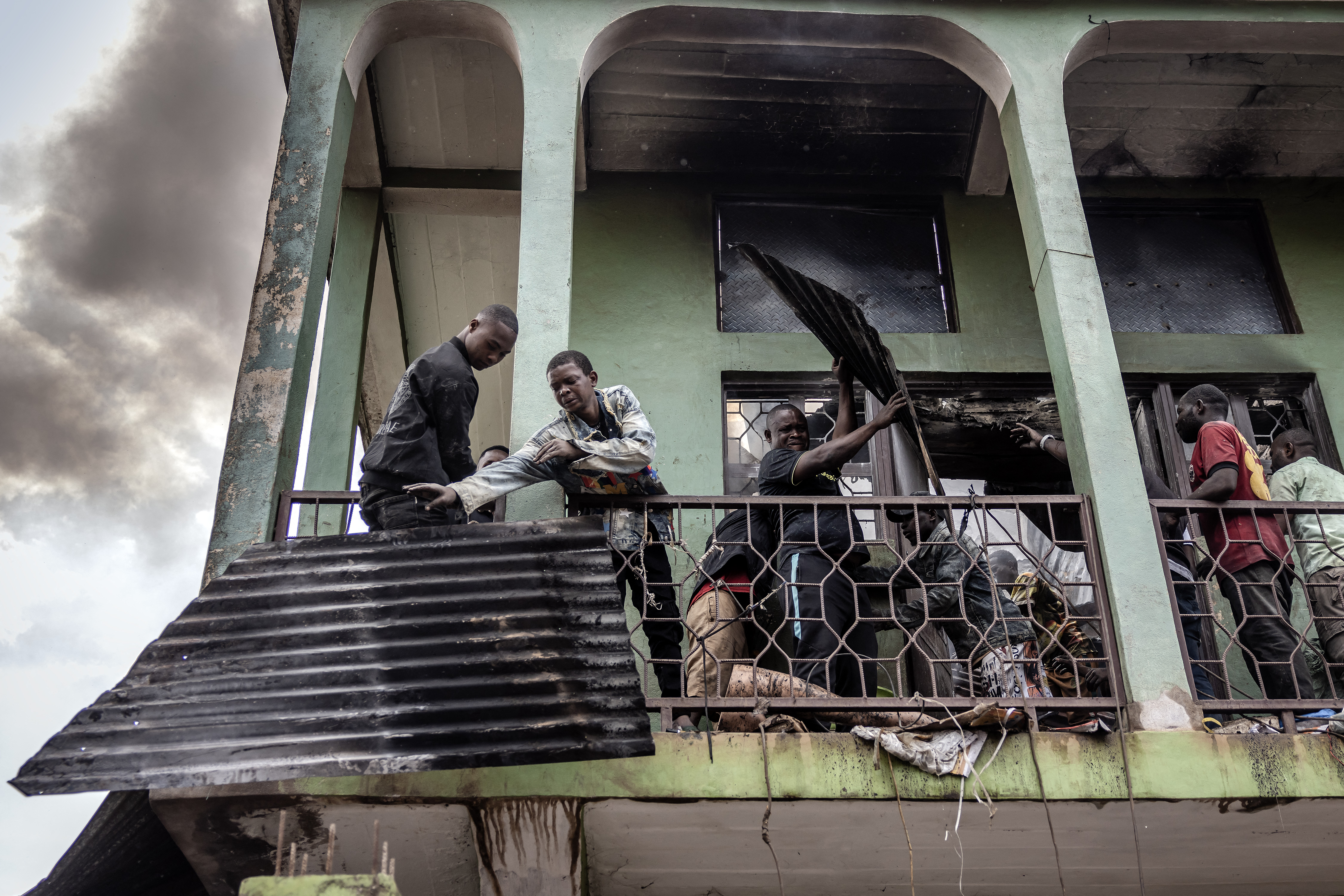 Workers remove pieces of iron sheet from the burned and destroyed market [File: Luis Tato/ AFP]