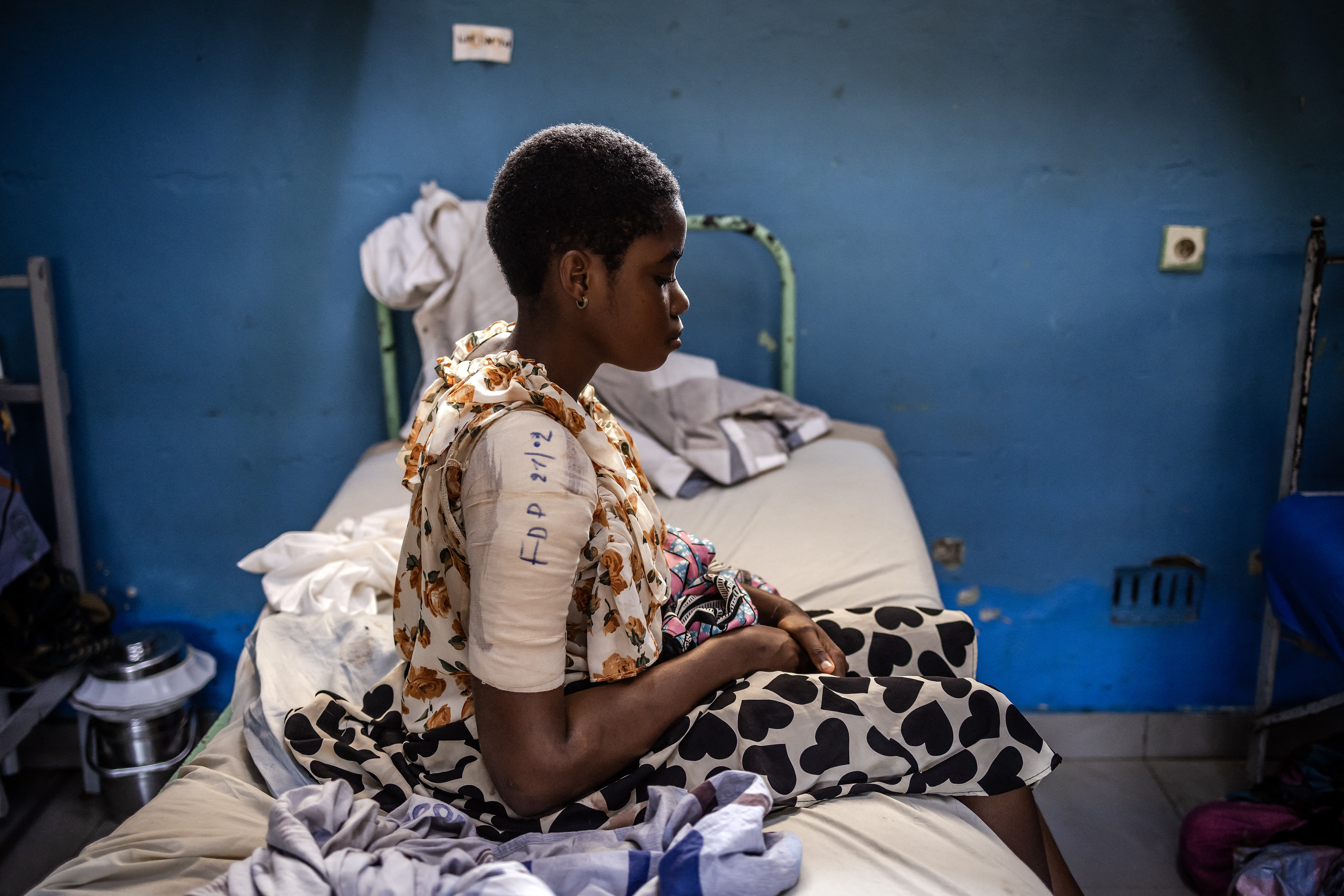 Chancelline Joari nurses a gunshot wound on her arm while sitting on her hospital bed.