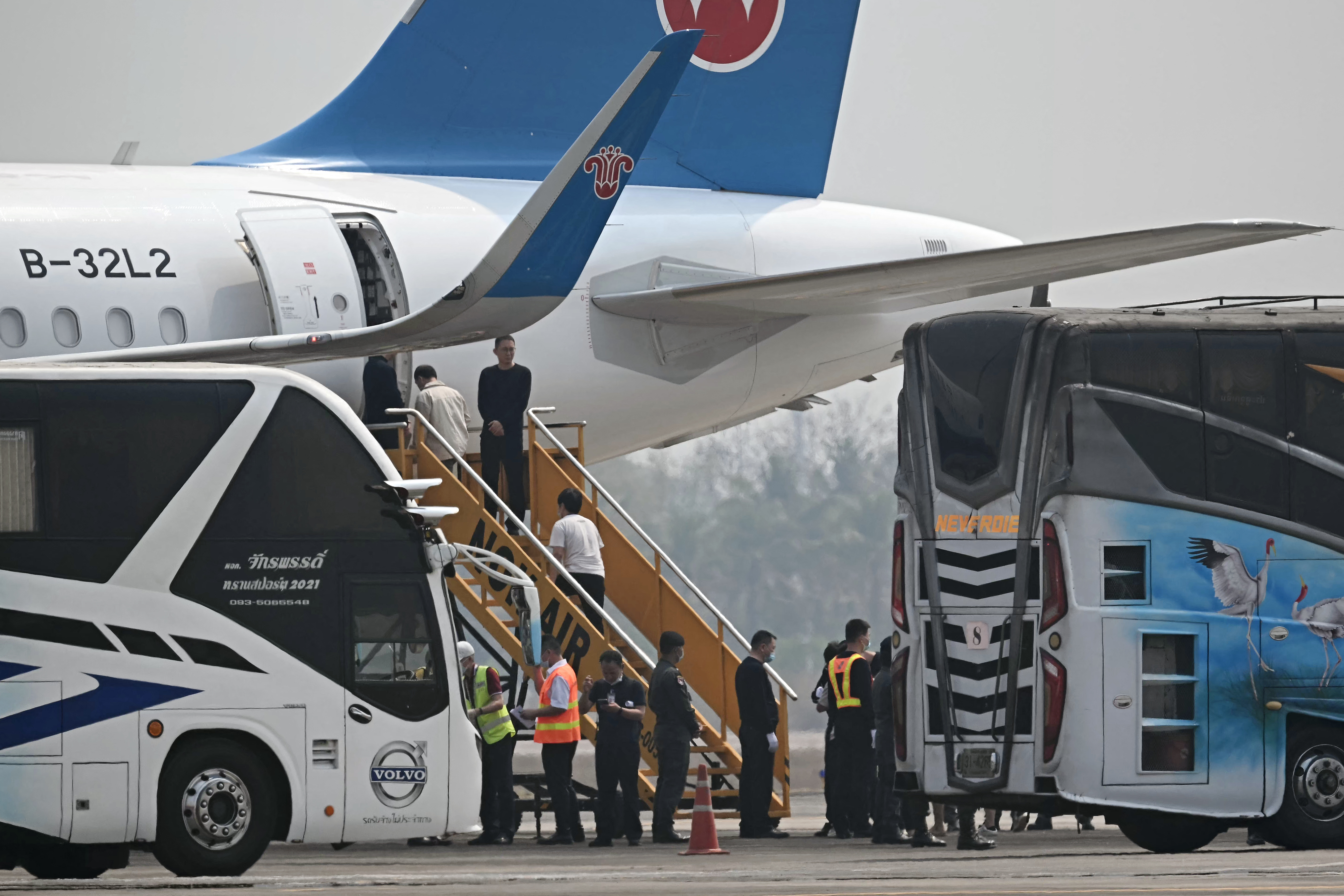 Alleged scam centre workers and victims from China handed over from Myanmar board a plane.