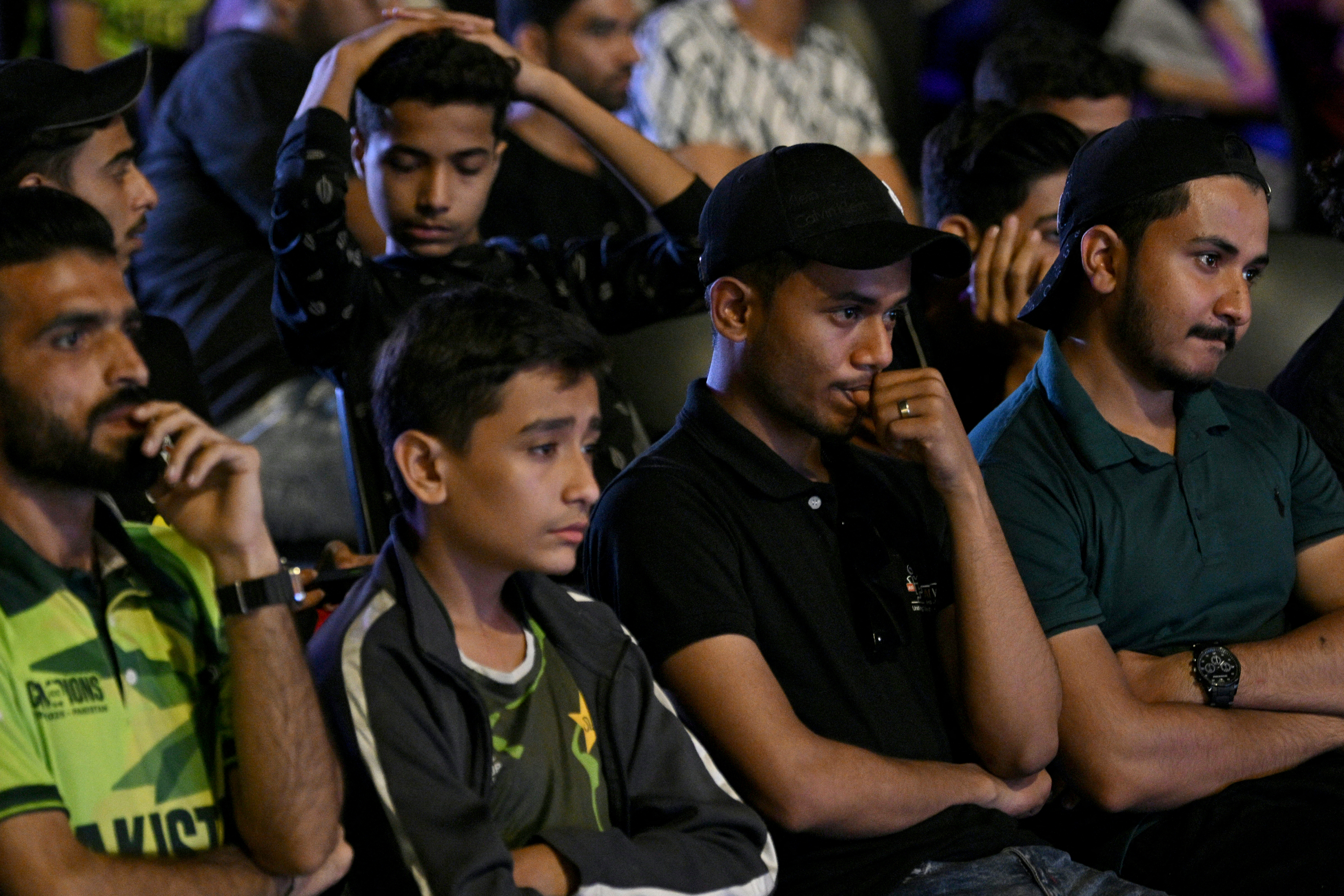 Cricket fans react as they watch a live broadcast of the ICC Champions Trophy one-day international (ODI) cricket match between India and Pakistan in Dubai, on a big in Karachi on February 23, 2025. (Photo by Asif HASSAN / AFP)