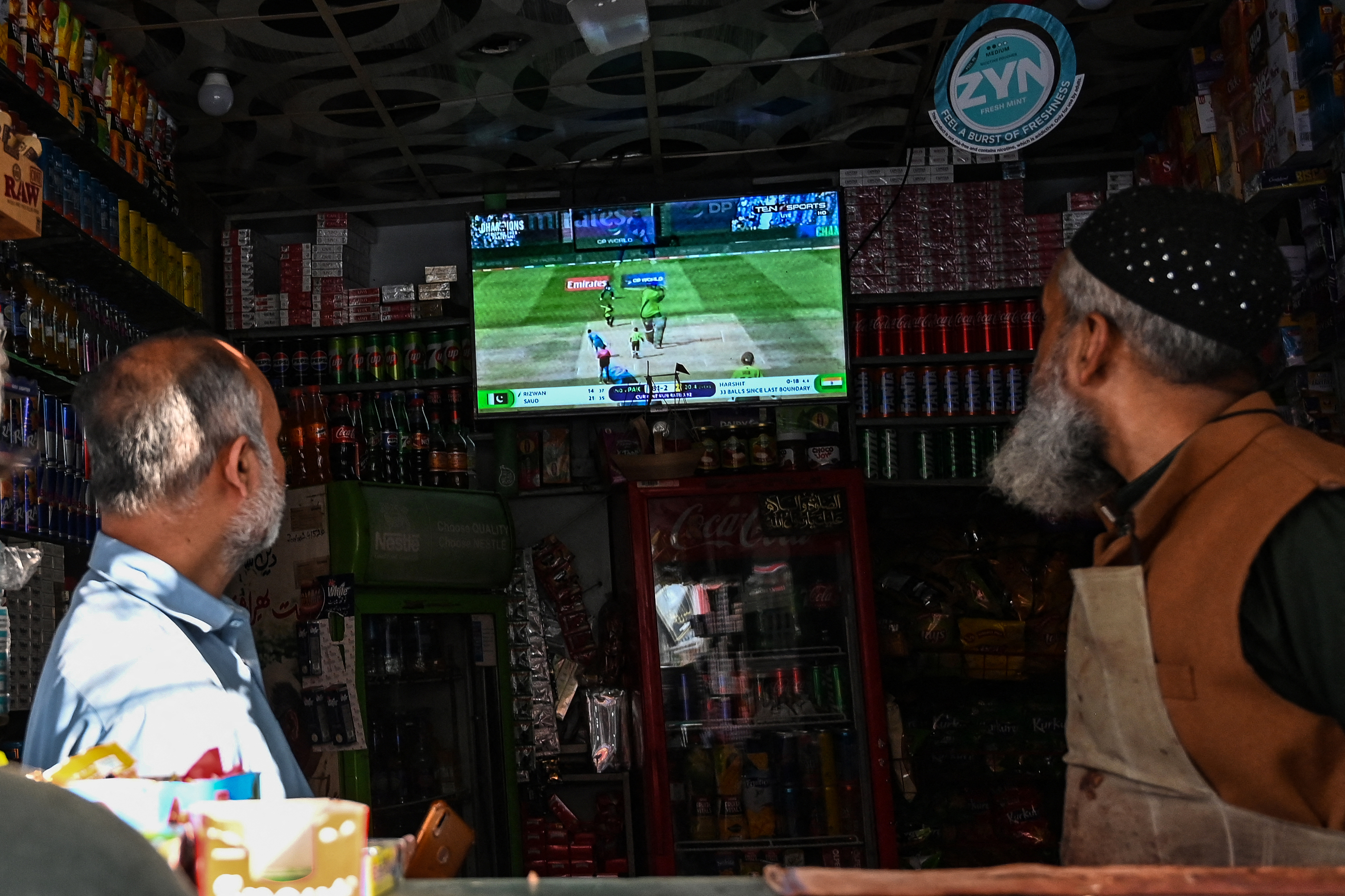People watch a live broadcast at a shop in Lahore on February 23, 2025, screening the ICC Champions Trophy one-day international (ODI) cricket match between Pakistan and India in Dubai. (Photo by Aamir QURESHI / AFP)