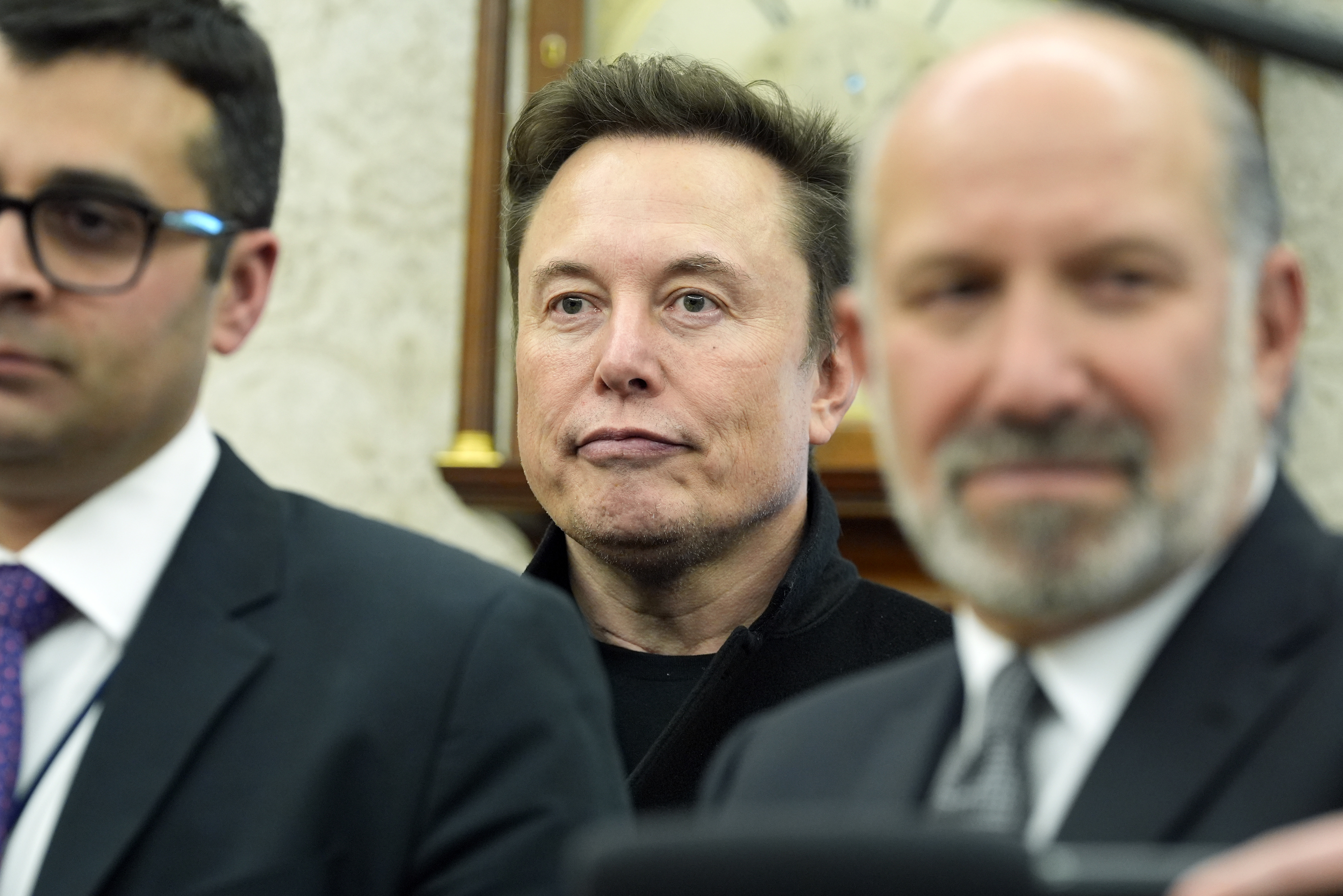 Elon Musk behind officials in the Oval Office.