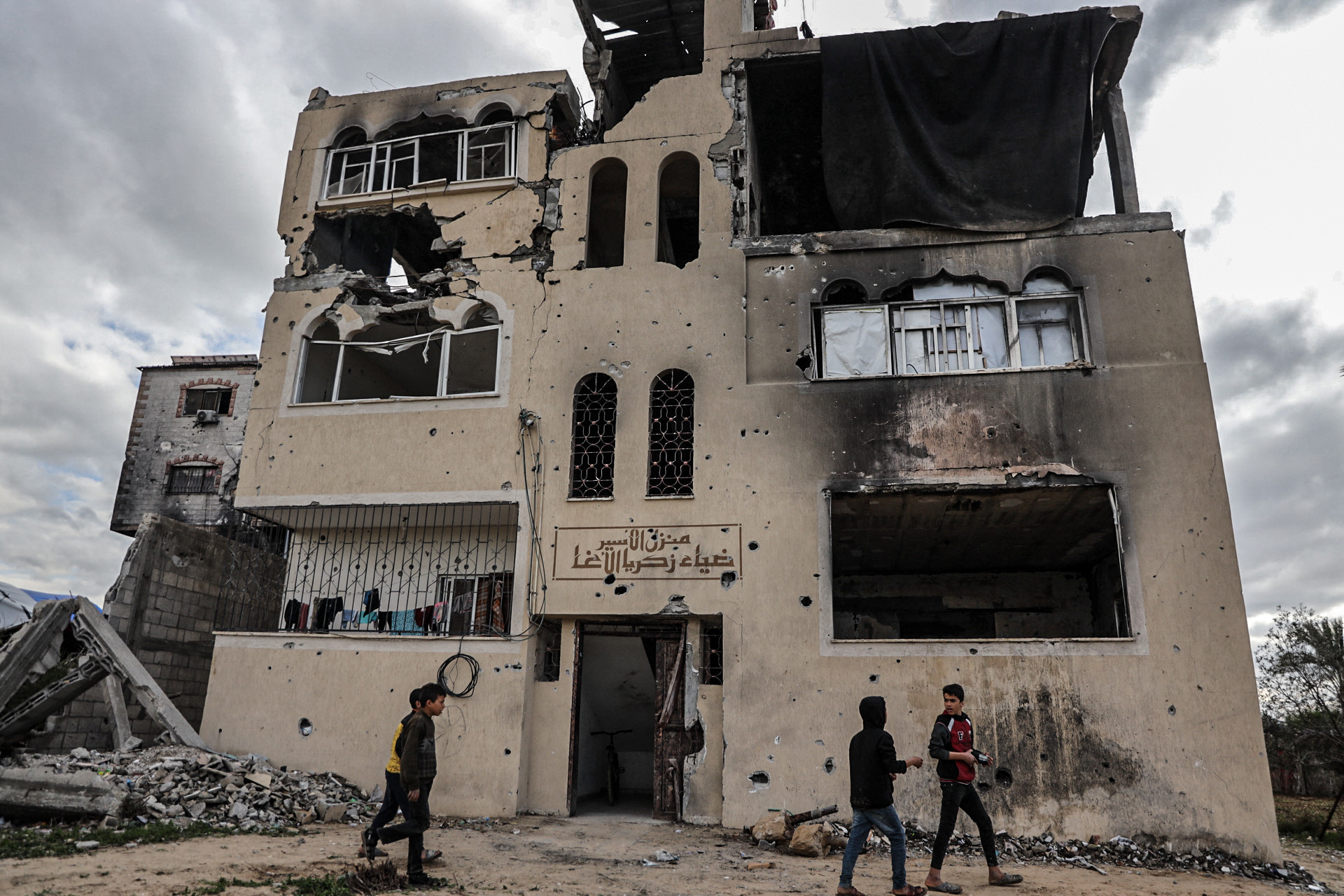 The family home in Khan Younes, badly damaged by Israeli attacks, with the inscription 'Home of the prisoner Diaa Al-Agha' over the door