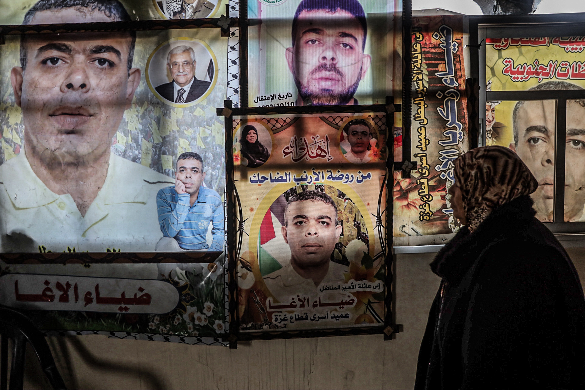Najat Al-Agha stands in front of a collage of posters featuring Diaa that hang in their destroyed home