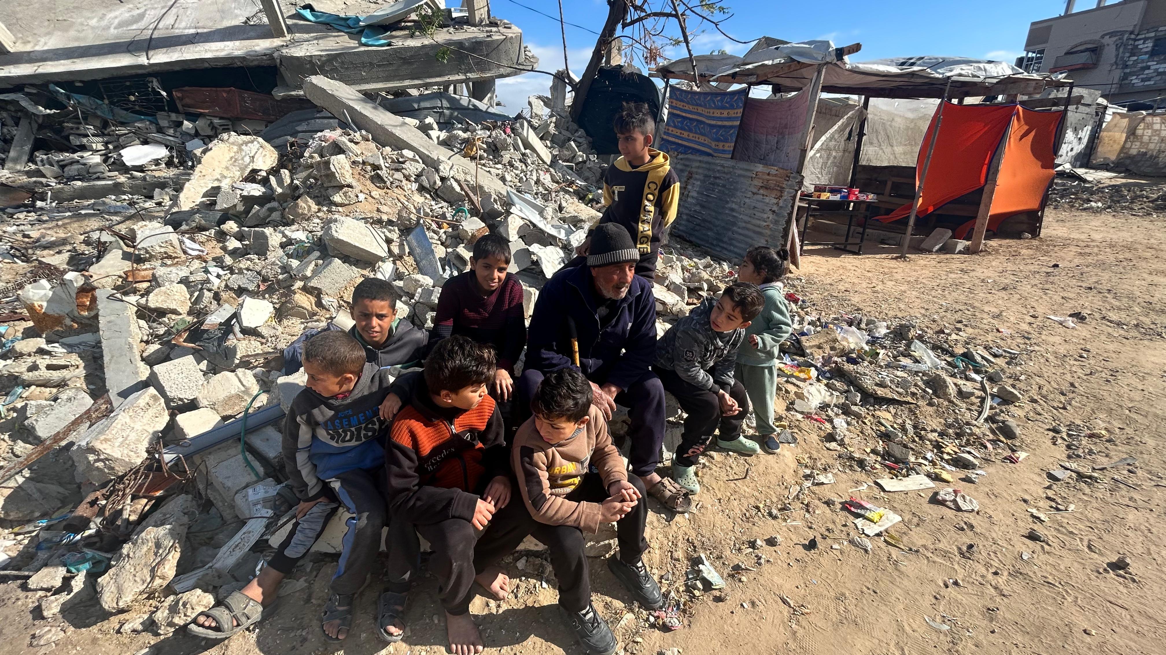 Fathi Abu al-Saeed sits on rubble with children gathered around him 