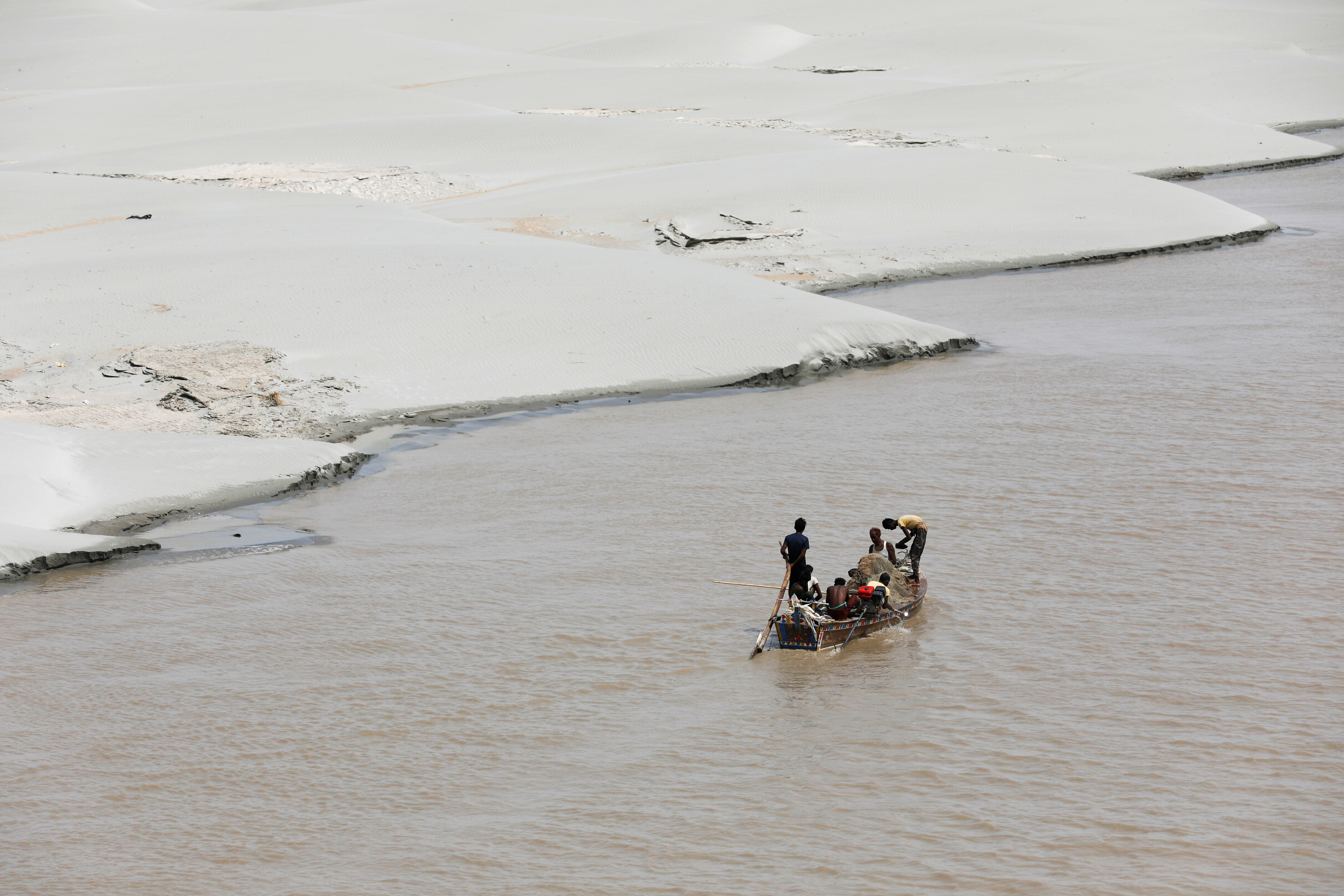 Fishermen are seen in a sailboat for fishing as they pass along the dry side of the Indus River in Hyderabad, Pakistan September 3, 2018. REUTERS/Akhtar Soomro