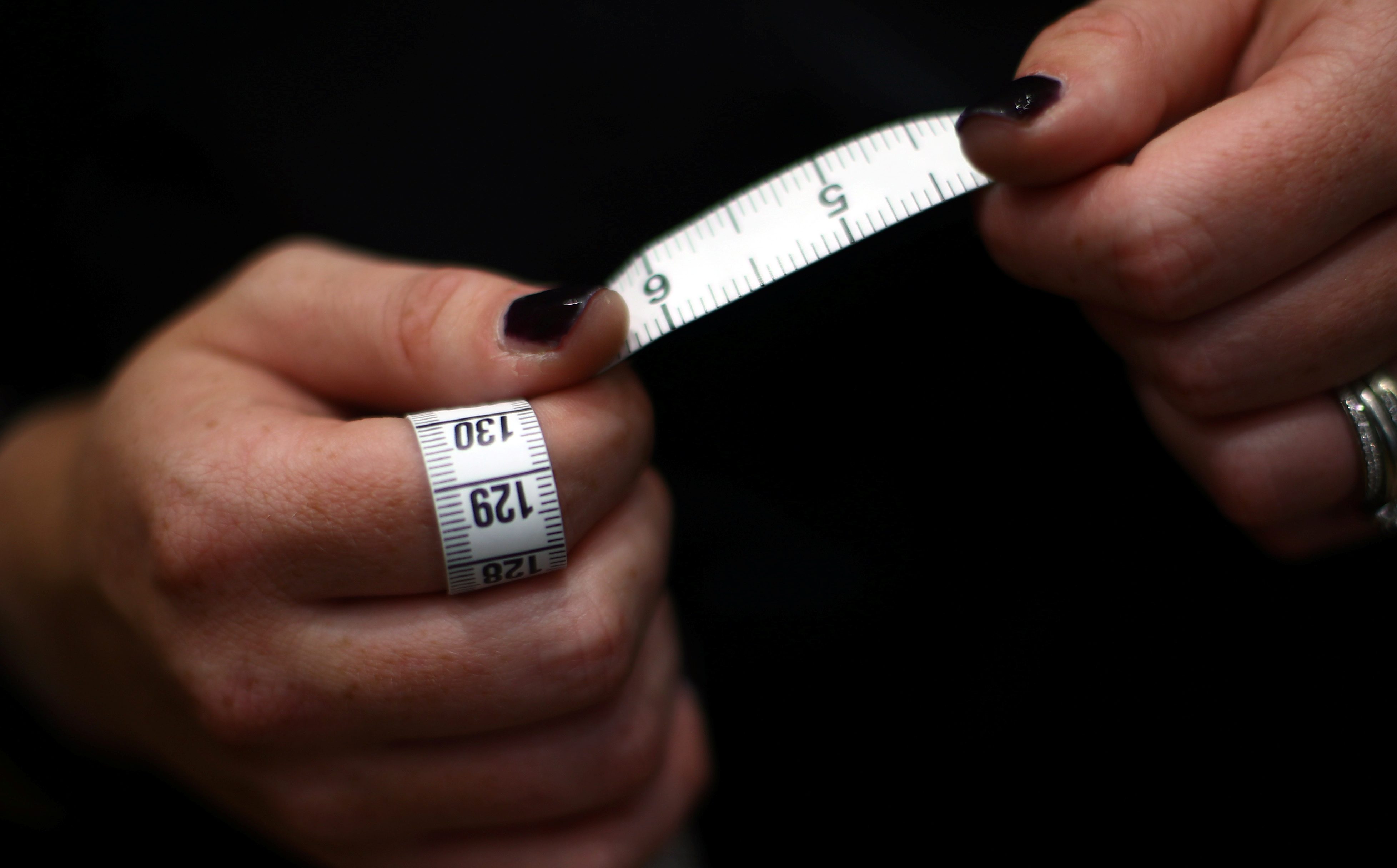 A tape measure is held by a tailor at Maurice Sedwell tailors on Saville Row,
