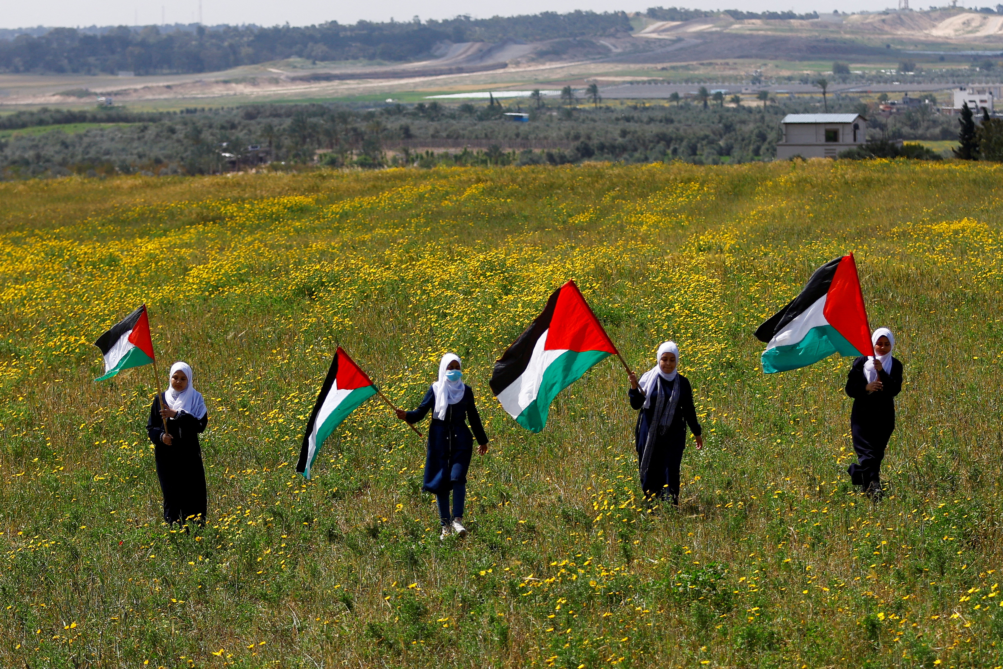 Palestinians hold flags as they mark 'Land Day', an annual commemoration of six Arab citizens of Israel who were killed by Israeli security forces during demonstrations over land confiscations in 1976, in the southeast of Gaza City March 30, 2023. REUTERS/Ibraheem Abu Mustafa TPX IMAGES OF THE DAY