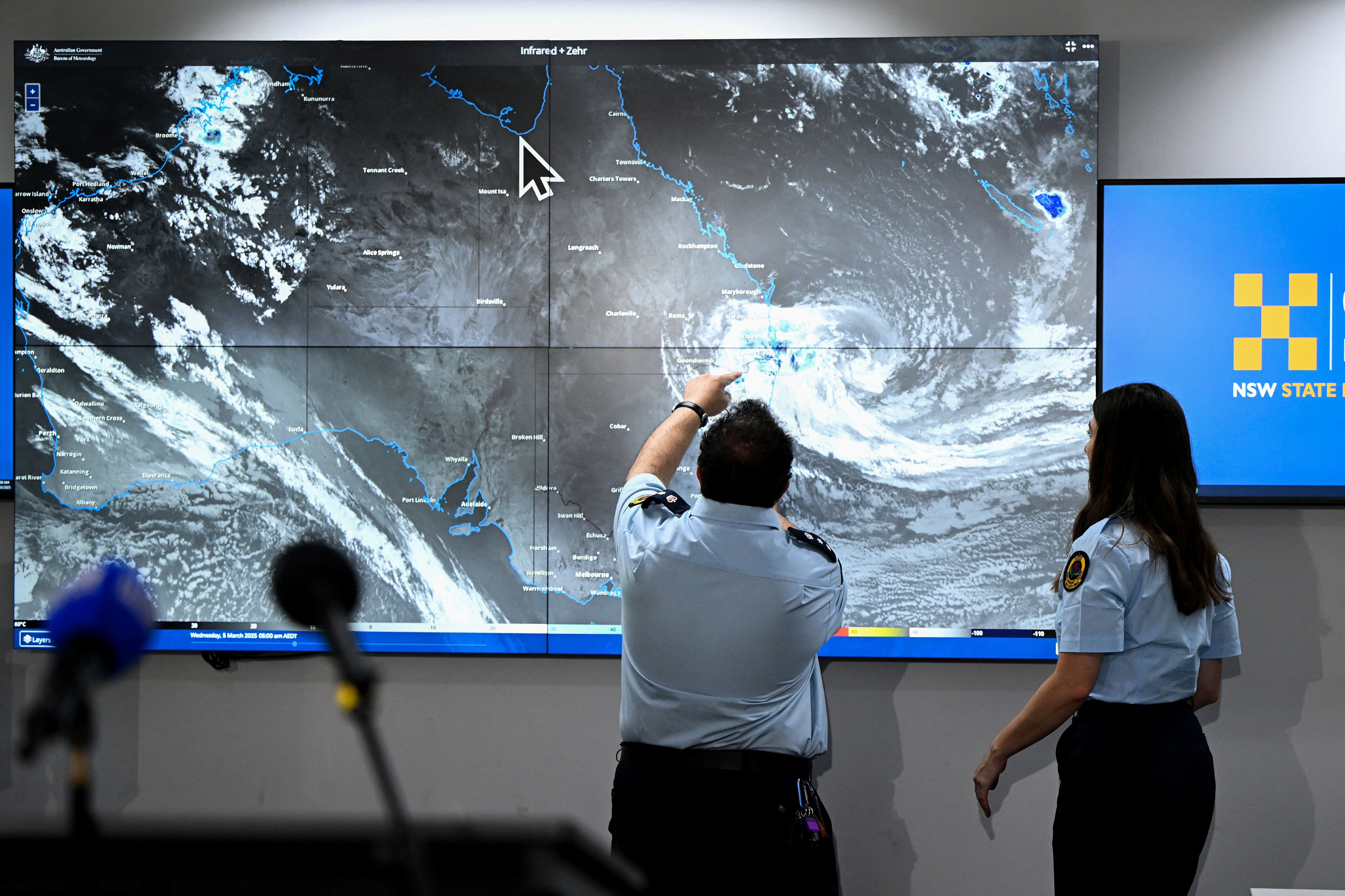 Members of the SES inspect Tropical Cyclone Alfred on the Bureau of Meteorology satellite view at the NSW SES Rhodes Headquarters