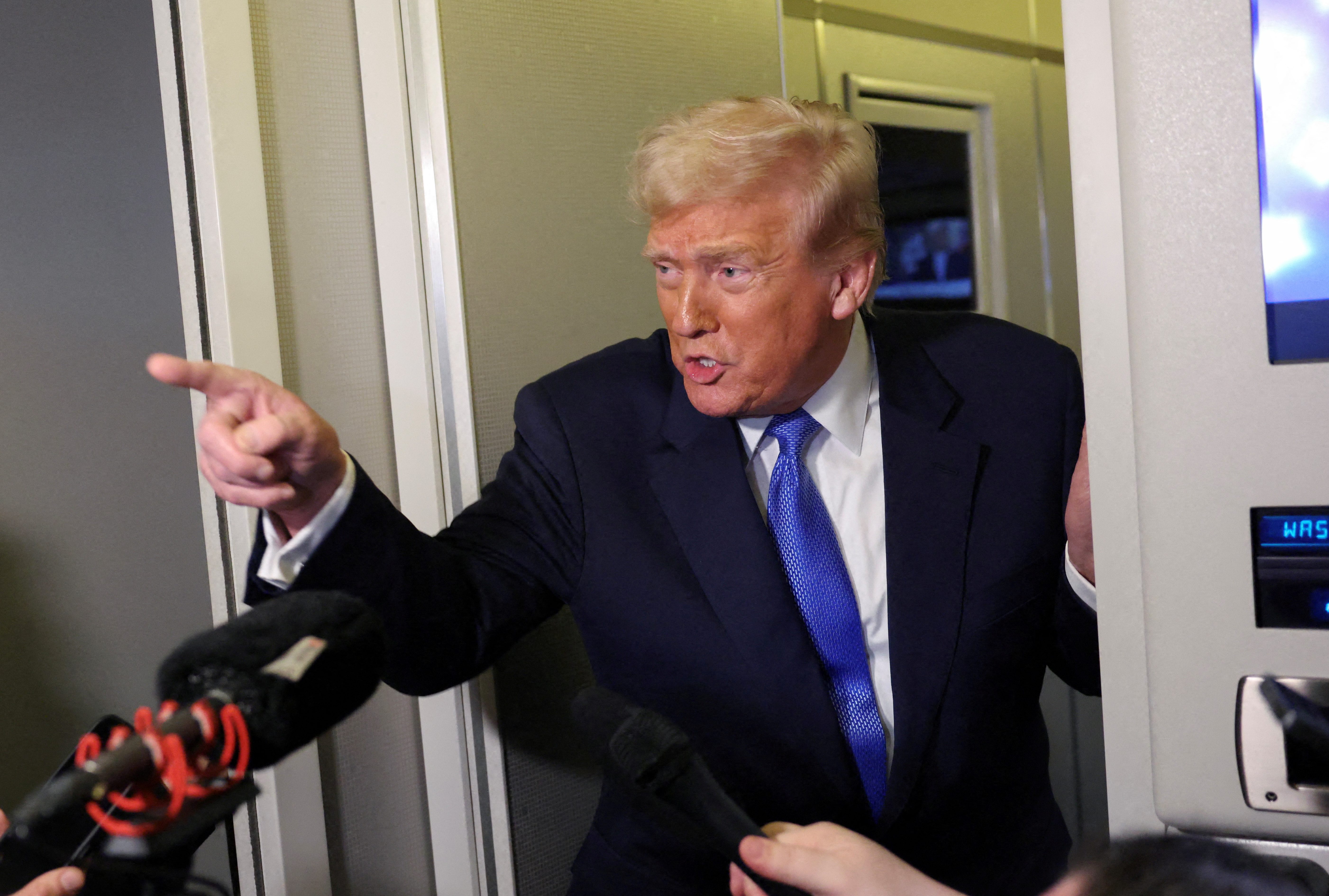 US President Donald Trump speaks to reporters as White House Press Secretary Karoline Leavitt stands with him.