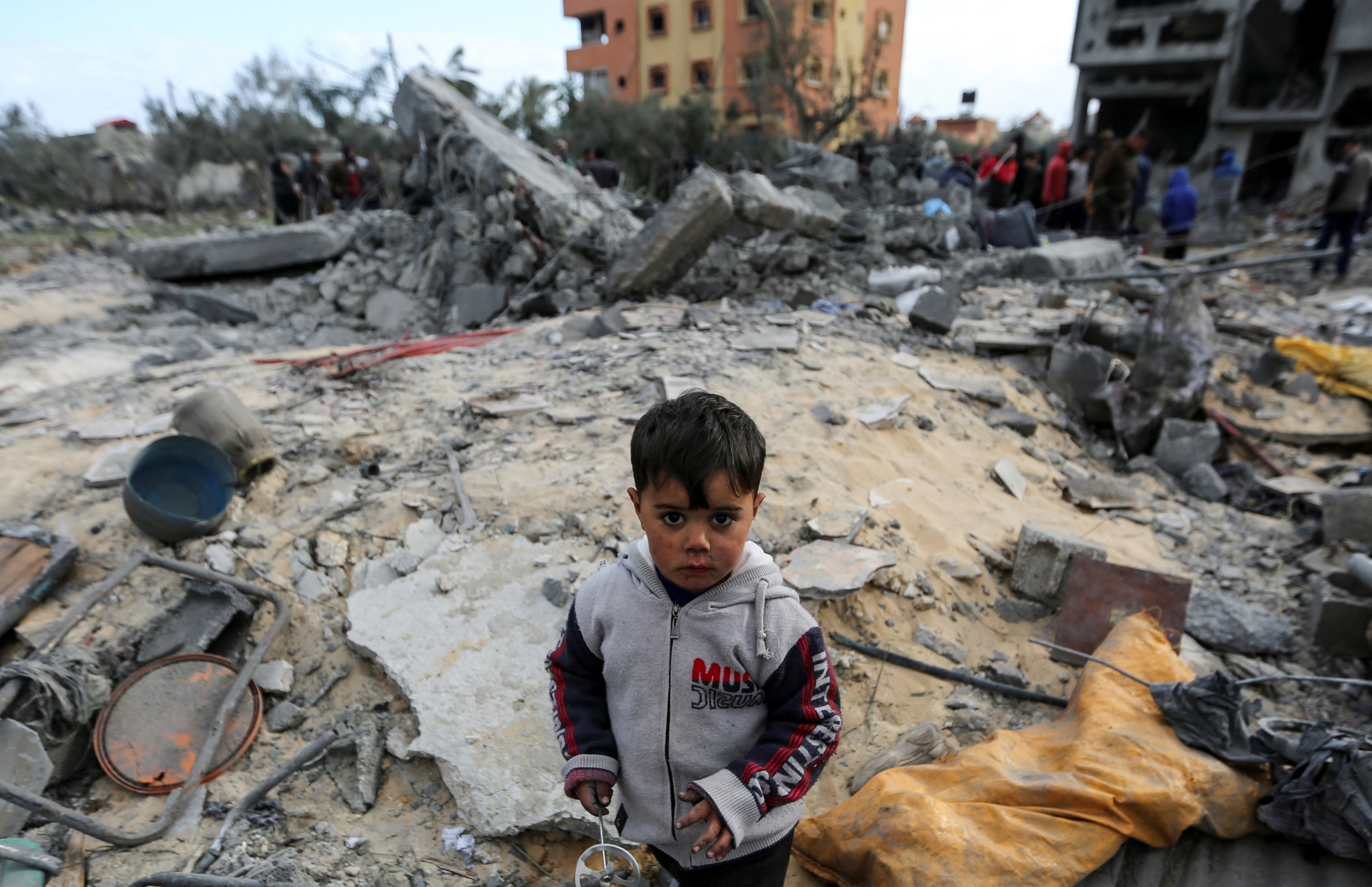 A child looks on as Palestinians inspect the site of an Israeli strike on a house, in Khan Younis in the southern Gaza Strip March 20, 2025. REUTERS/Hatem Khaled
