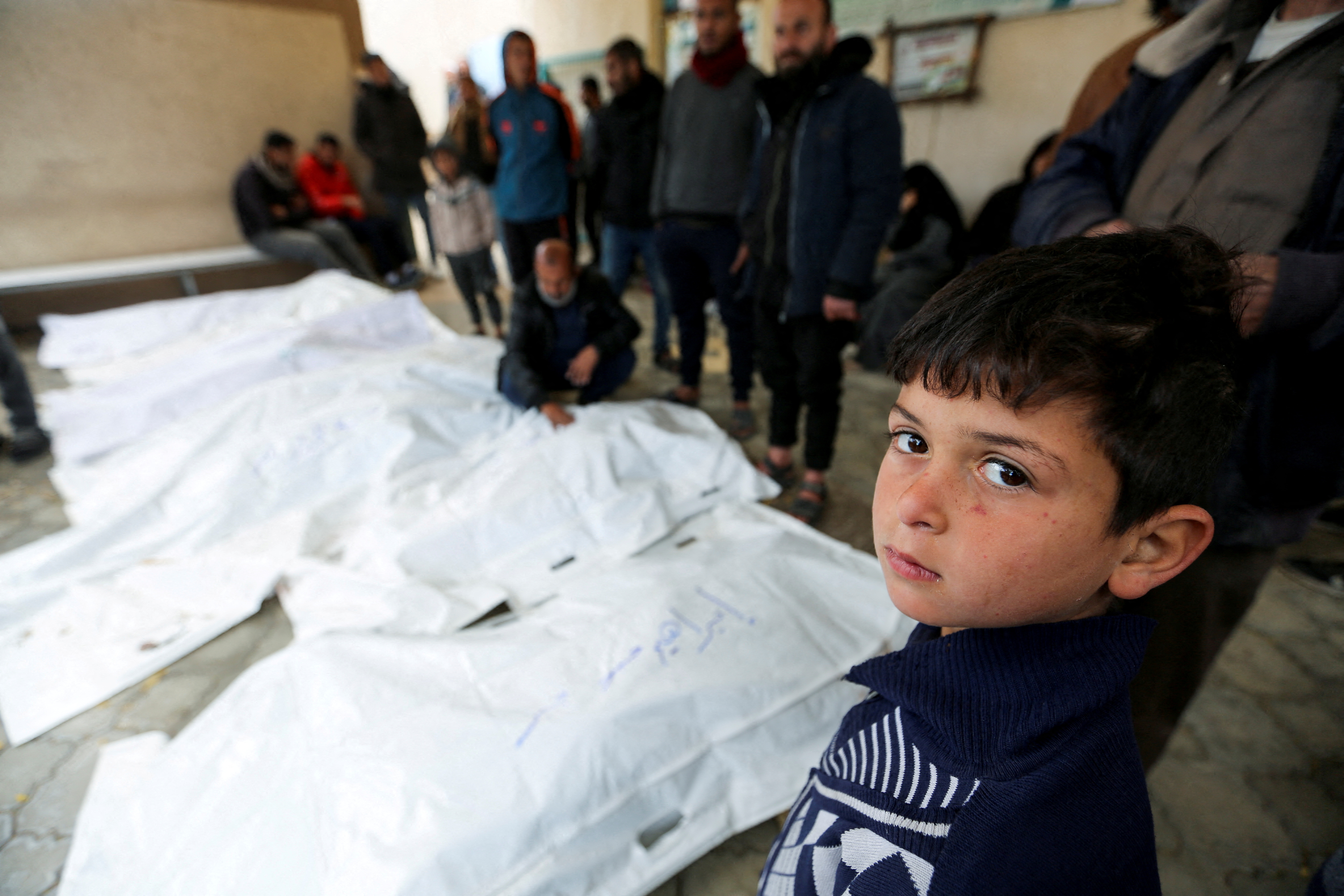 A child looks on as people mourn Palestinians killed in Israeli strikes at the European hospital in Khan Younis