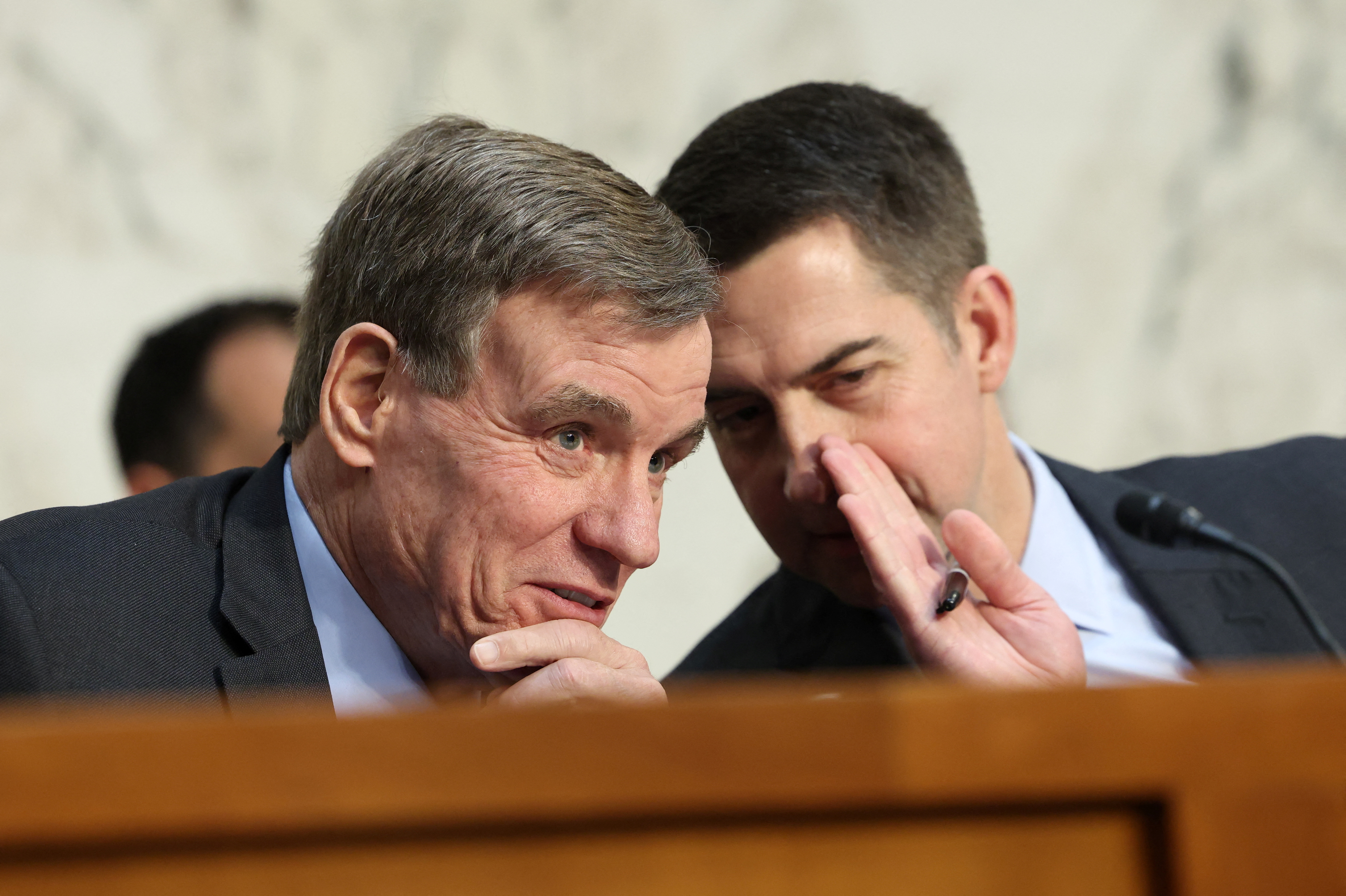 Tom Cotton whispers to Mark Warner at a Senate Intelligence meeting.