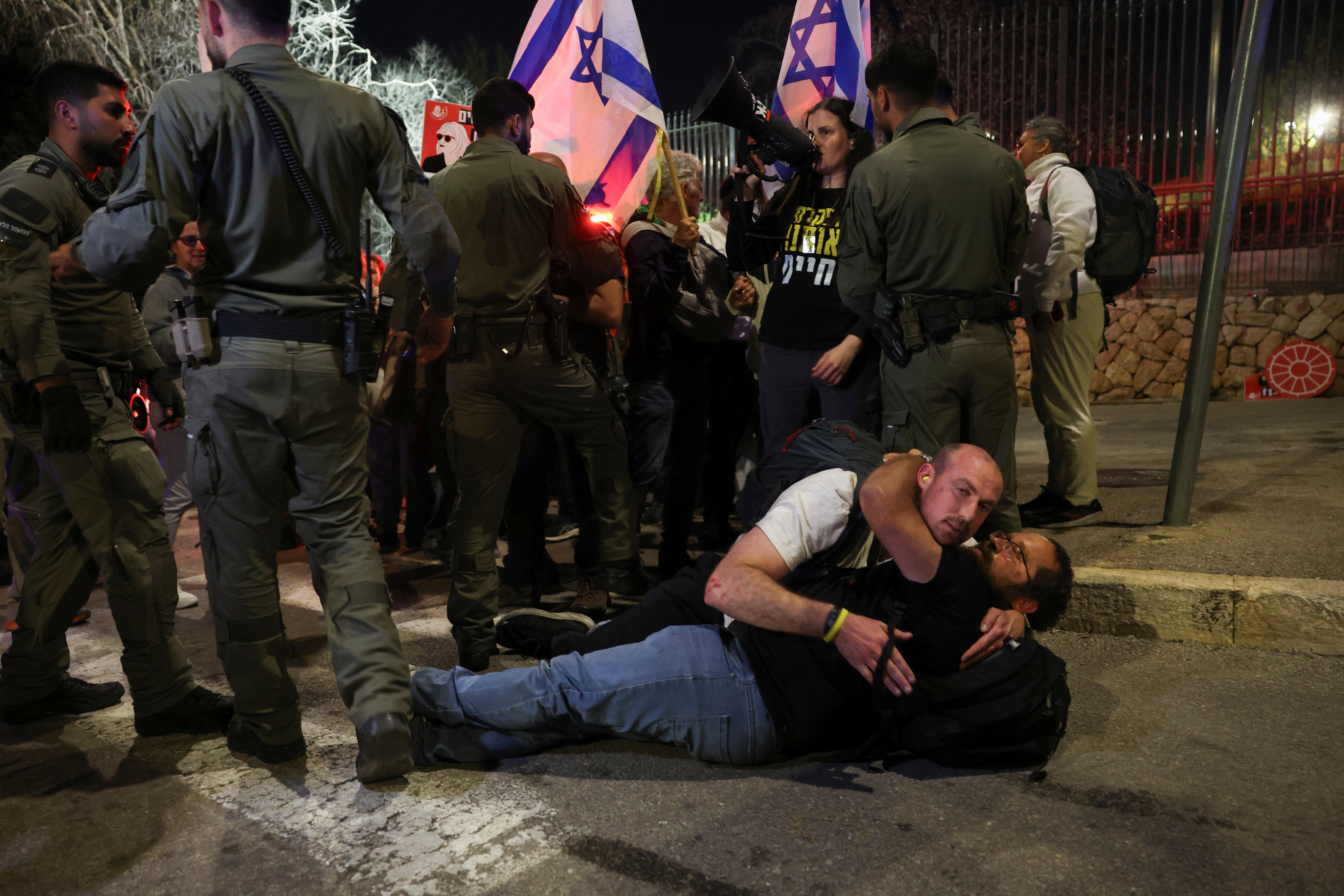 Demonstrators embrace on the ground as members of security forces remove protesters trying to block the entrance to the Knesset, Israel Parliament, protesting against moves by the Israeli government to fire the Attorney General Gali Baharav Miara and the dismissal of top security agency chief, Ronen Bar, as well as the demand to release all hostages, in Jerusalem March 25, 2025 REUTERS/Ronen Zvulun