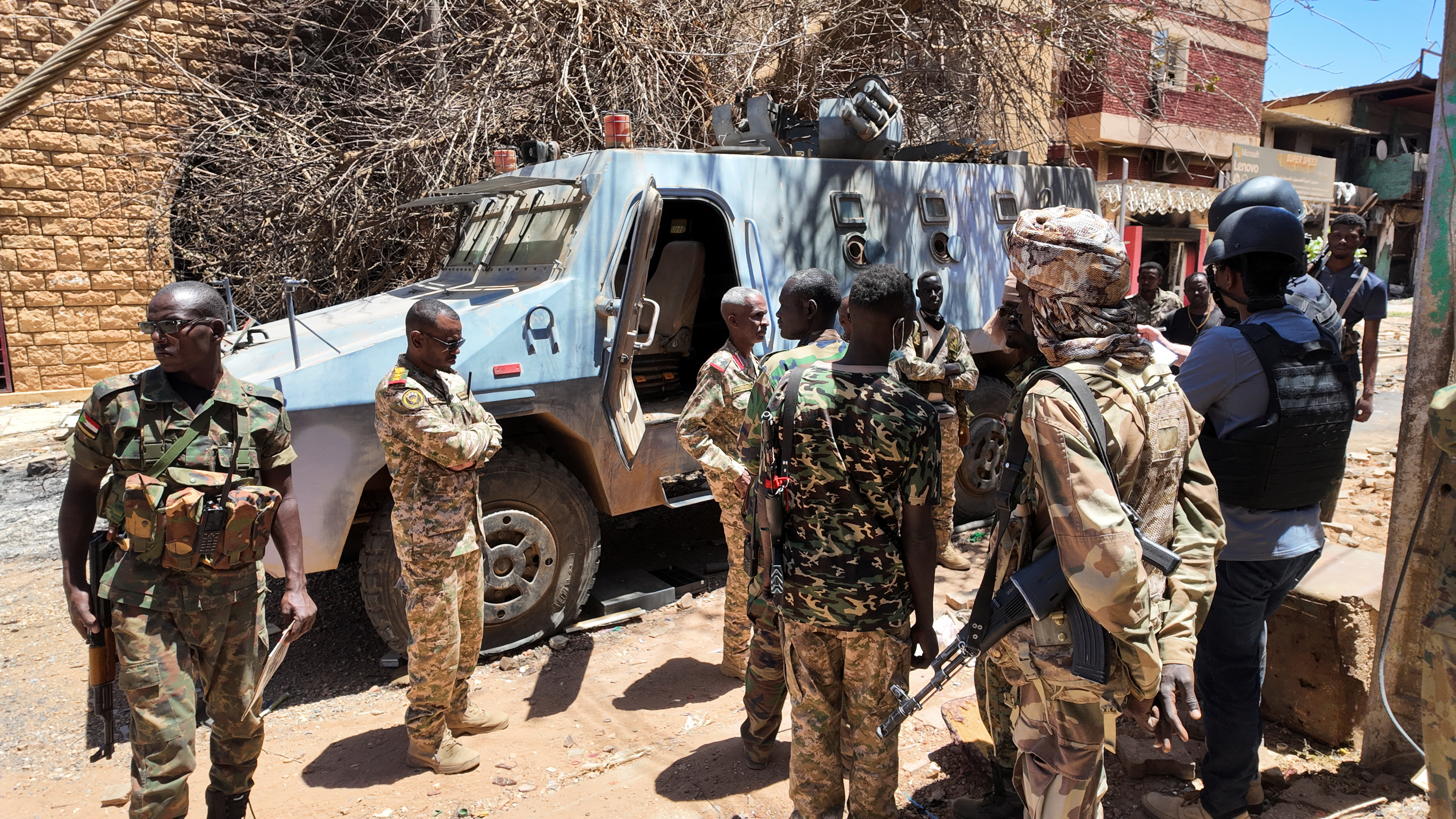 Members of the Sudanese army gather next to a destroyed military vehicle.
