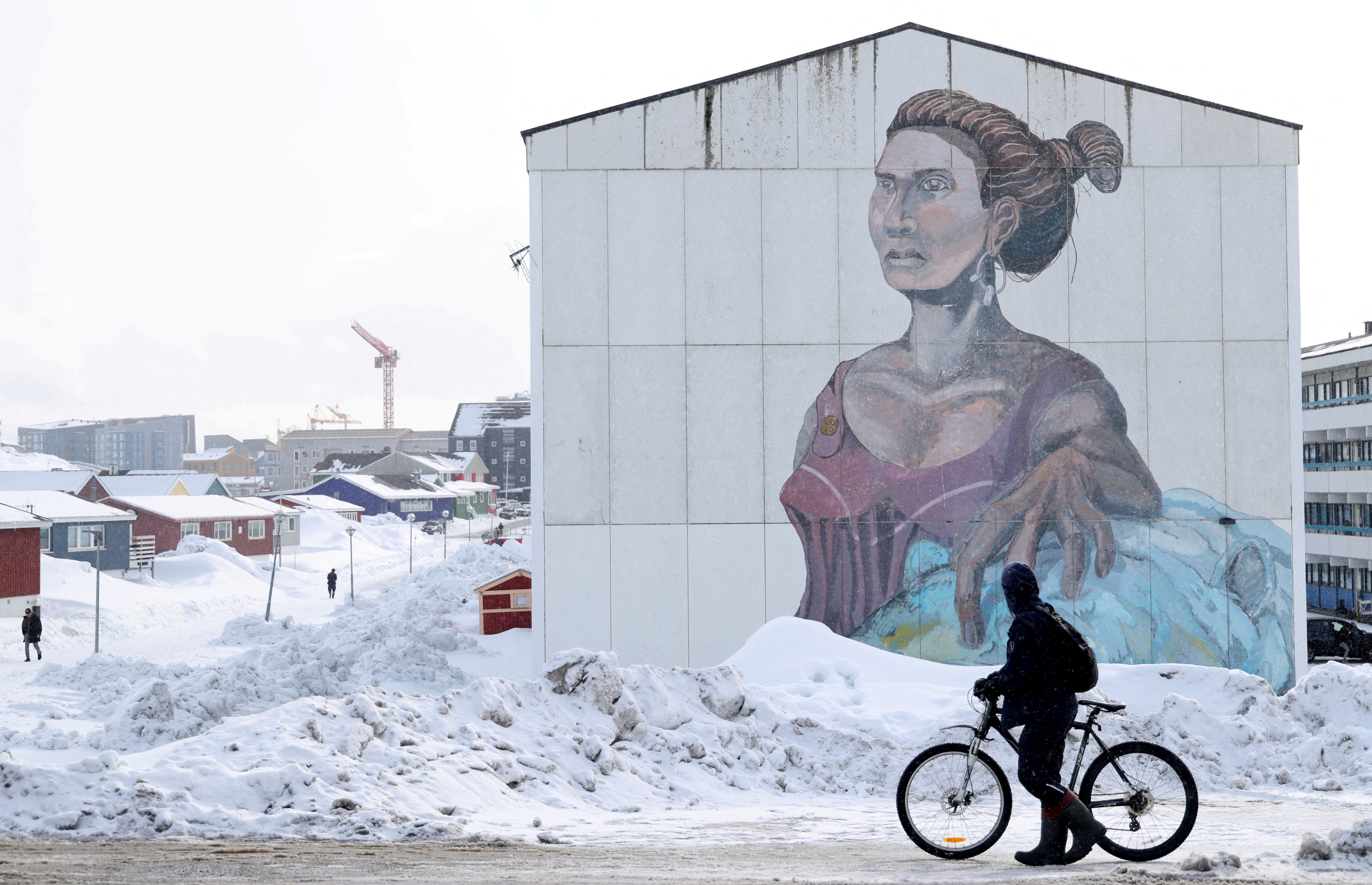 A man passes a social housing building with an Inuit mural in Nuuk, Greenland [Leonhard Foeger/Reuters]