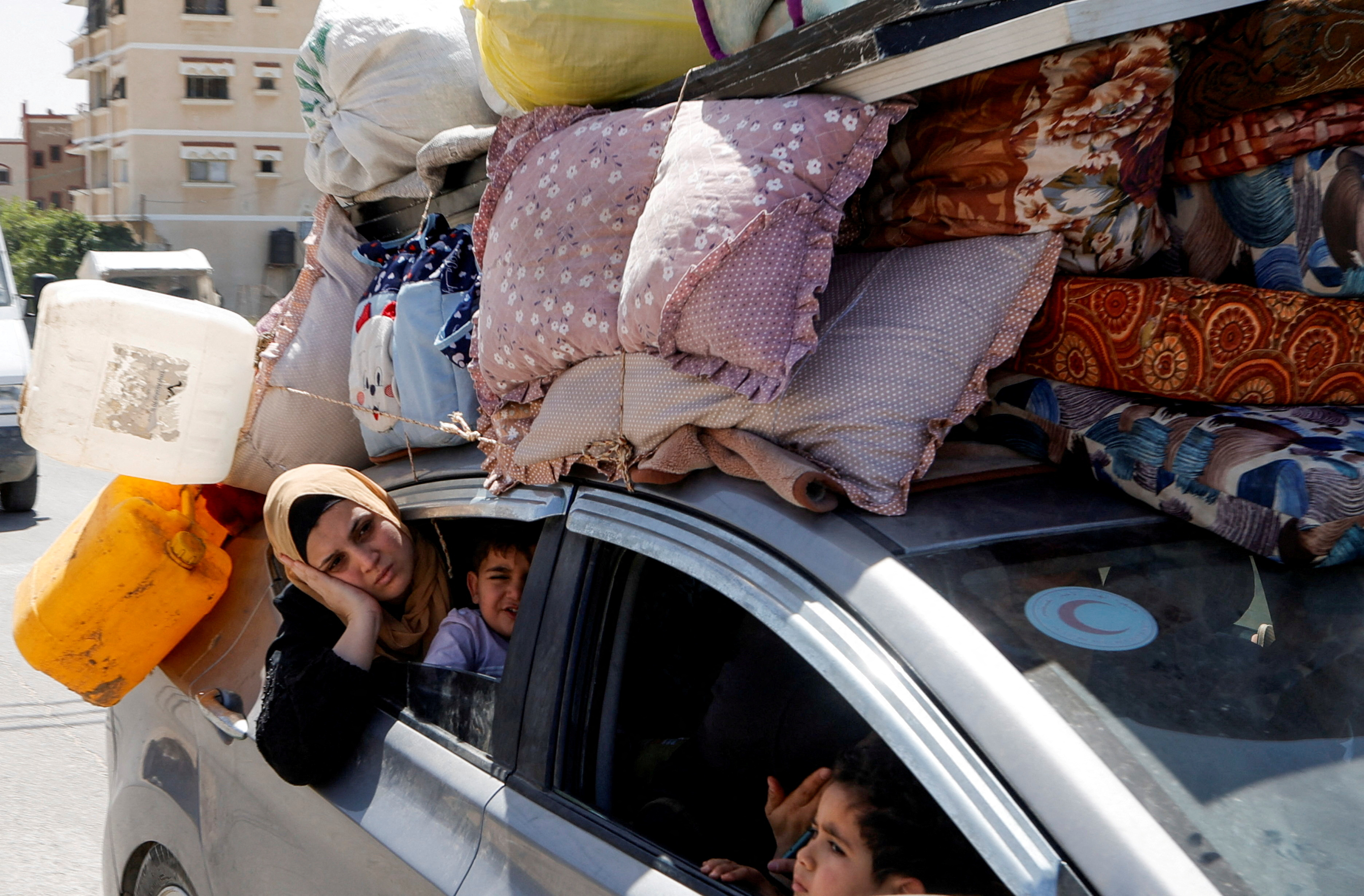 Palestinians use a car to transport belongings, as they make their way after fleeing areas around the southern city of Rafah