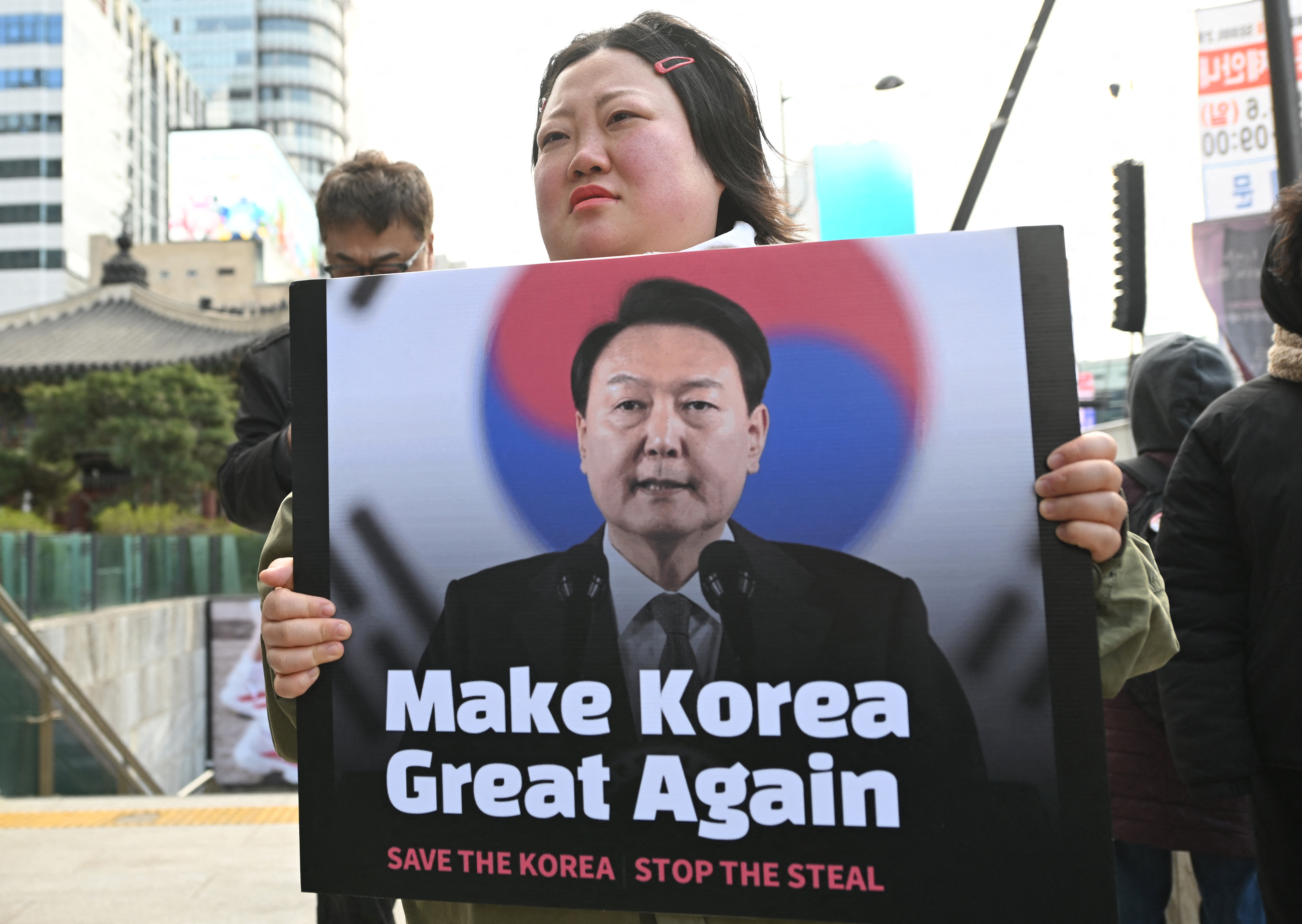 A woman holds a poster of impeached South Korean President Yoon Suk Yeol during a street rally.