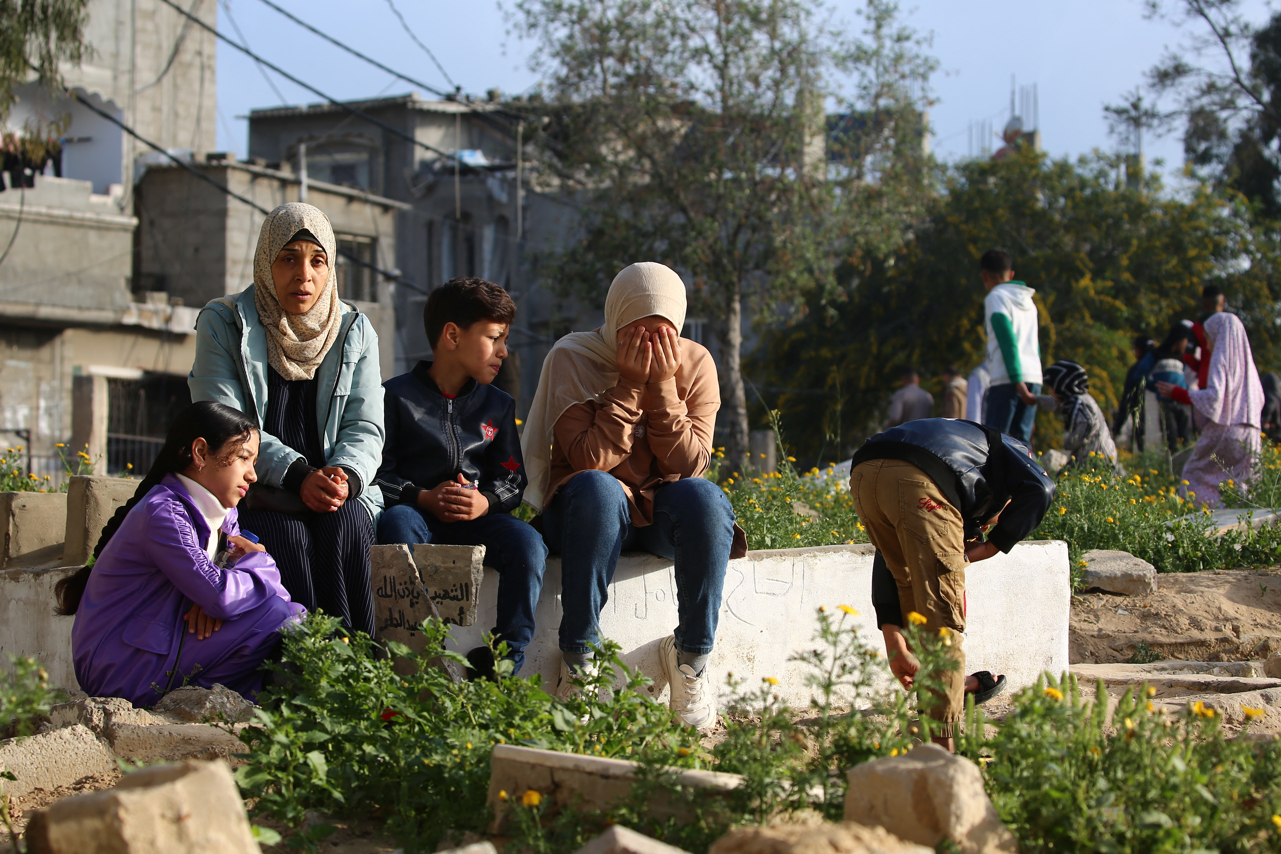 Palestinians visit the grave of a relative after Eid al-Fitr prayers, which marks the end of the holy fasting month of Ramadan, in the Nuseirat camp for Palestinian refugees