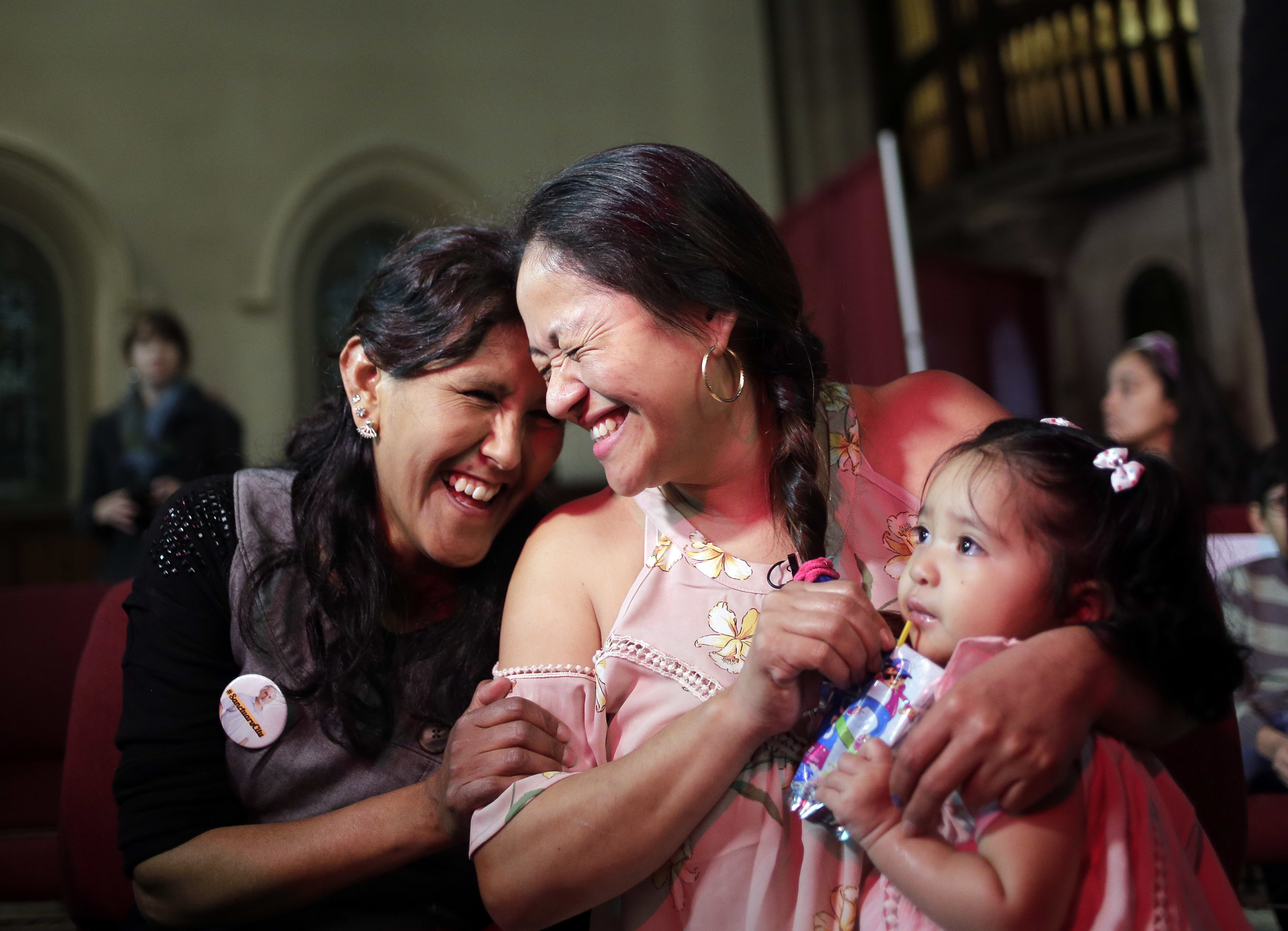 While holding her one-year-old daughter Camila Sanchez, Aura Hernandez, center, laughs with Jeanette Vizguerra