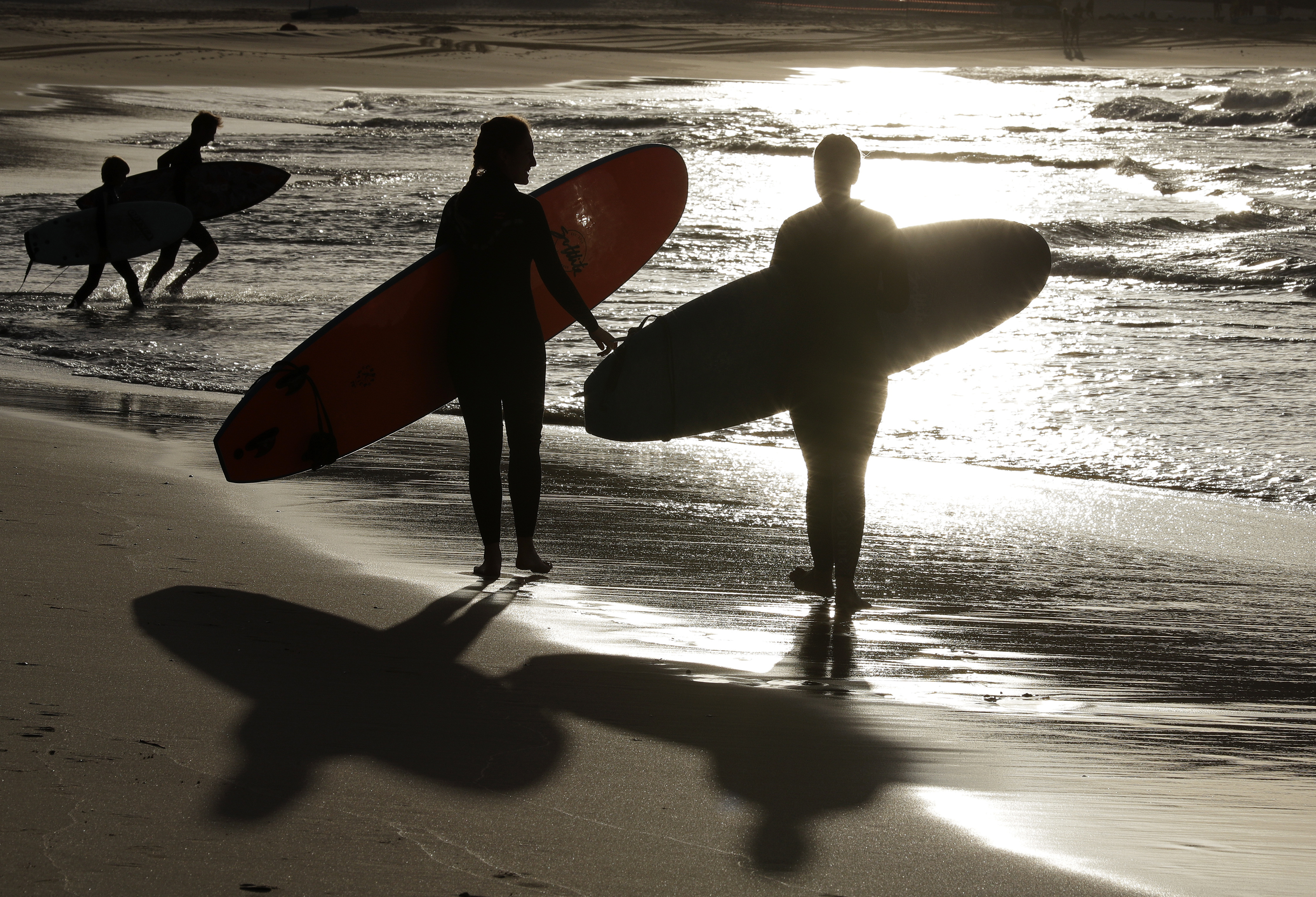 FILE - In this April 28, 2020, photo, surfers walk the beach in Sydney, Australia. Police in Australia say a 60-year-old surfer has been attacked and killed by a 10-foot shark off the coast of northern New South Wales state. (AP Photo/Rick Rycroft, File)
