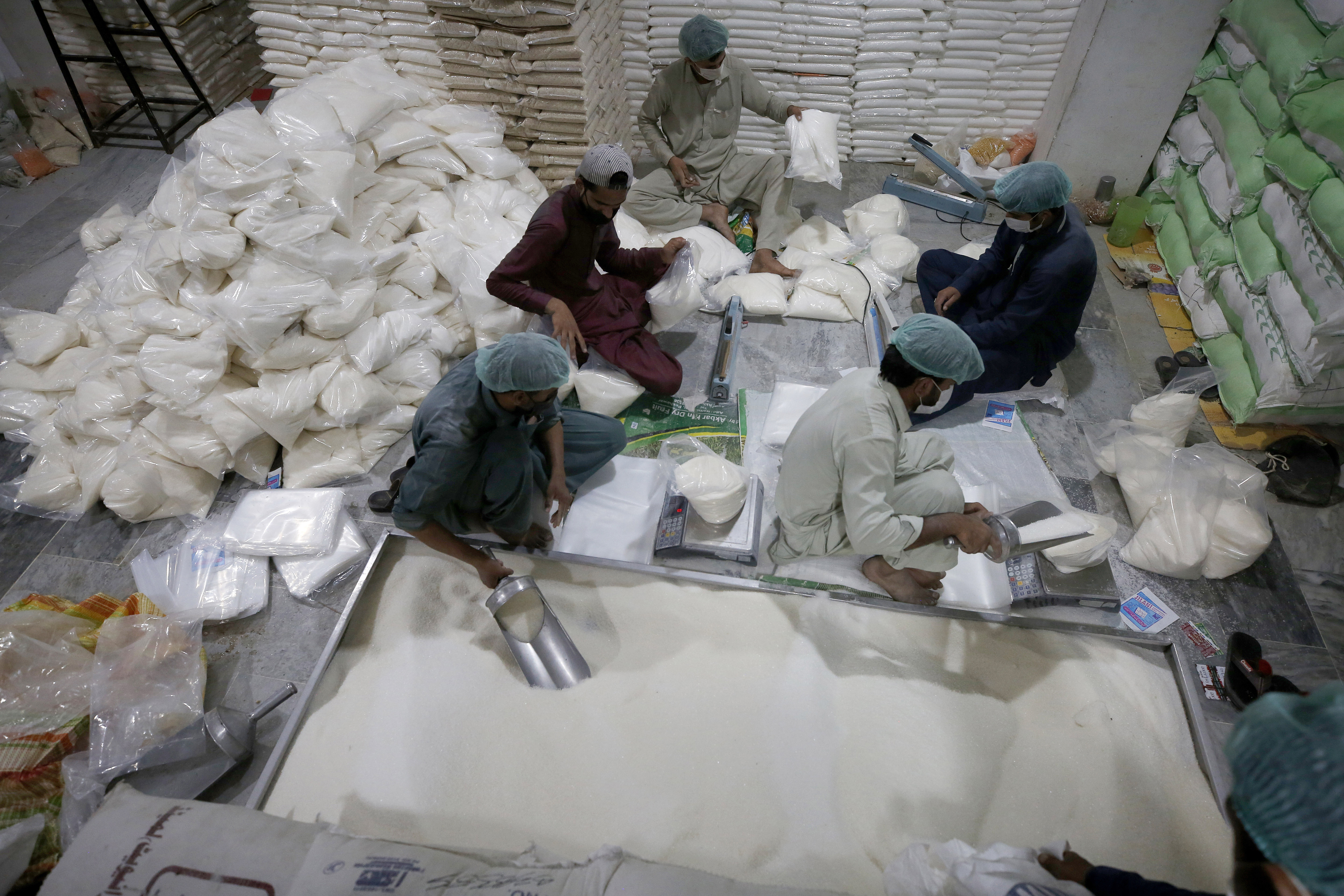 Workers of a charity group called "Alkhidmat Foundation Pakistan" prepare packets of sugar and other foodstuff to be distributed free among needy people for the upcoming Muslim fasting month of Ramadan, in Islamabad, Pakistan, Sunday, April 11, 2021. Ramadan begins with the new moon probably next week as Muslims around the world are trying to work out how to maintain the many cherished rituals of Islam's holiest month amid the coronavirus pandemic. (AP Photo/Anjum Naveed)