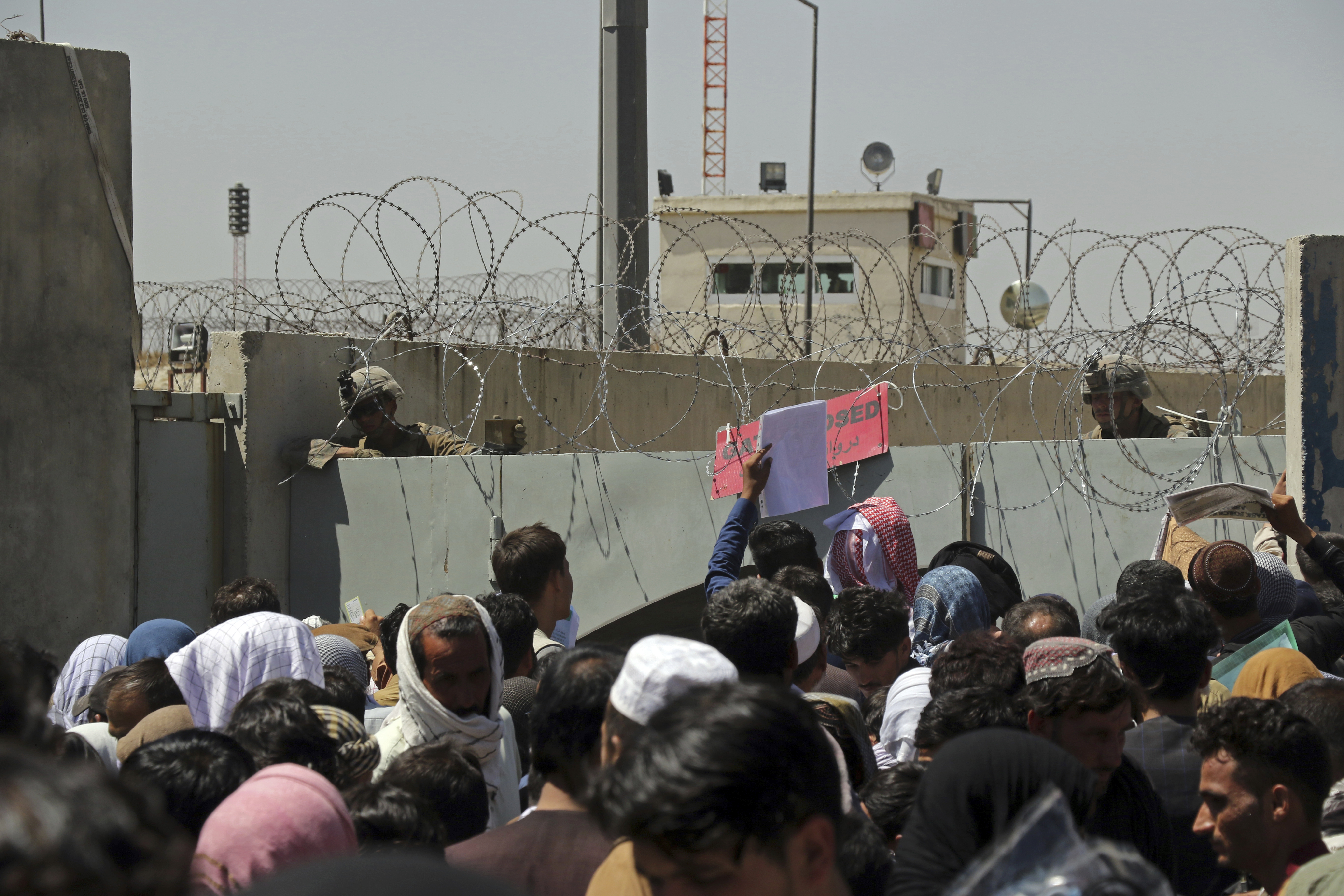 U.S. soldiers stand inside the airport as hundreds of people gather near an evacuation control checkpoint on the perimeter of the Hamid Karzai International Airport, in Kabul, Afghanistan, Thursday, Aug. 26, 2021. Western nations warned Thursday of a possible attack on Kabul's airport, where thousands have flocked as they try to flee Taliban-controlled Afghanistan in the waning days of a massive airlift. (AP Photo/Wali Sabawoon)
