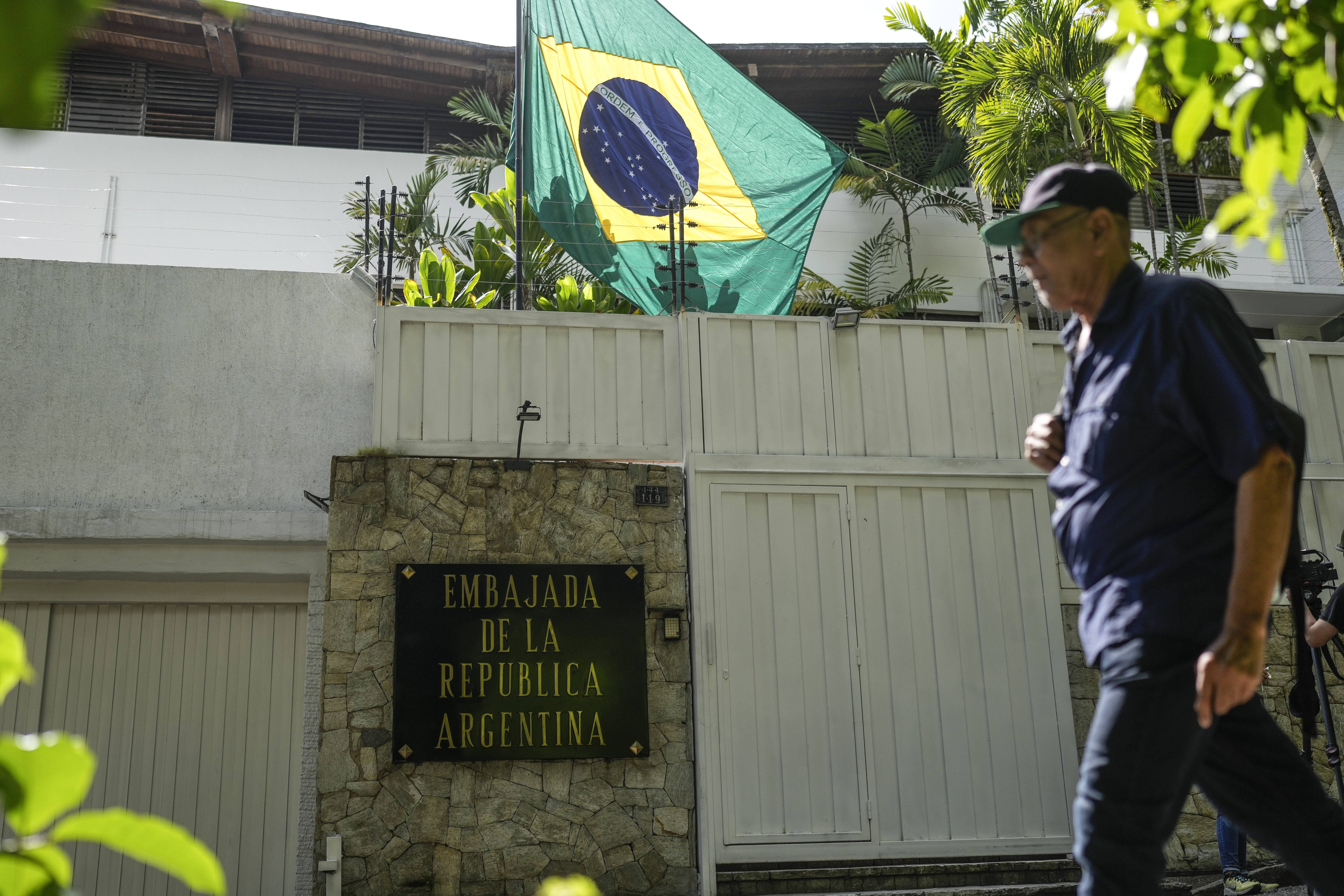 A Brazilian flag flies over the former Argentine embassy in Caracas as a guard walks by
