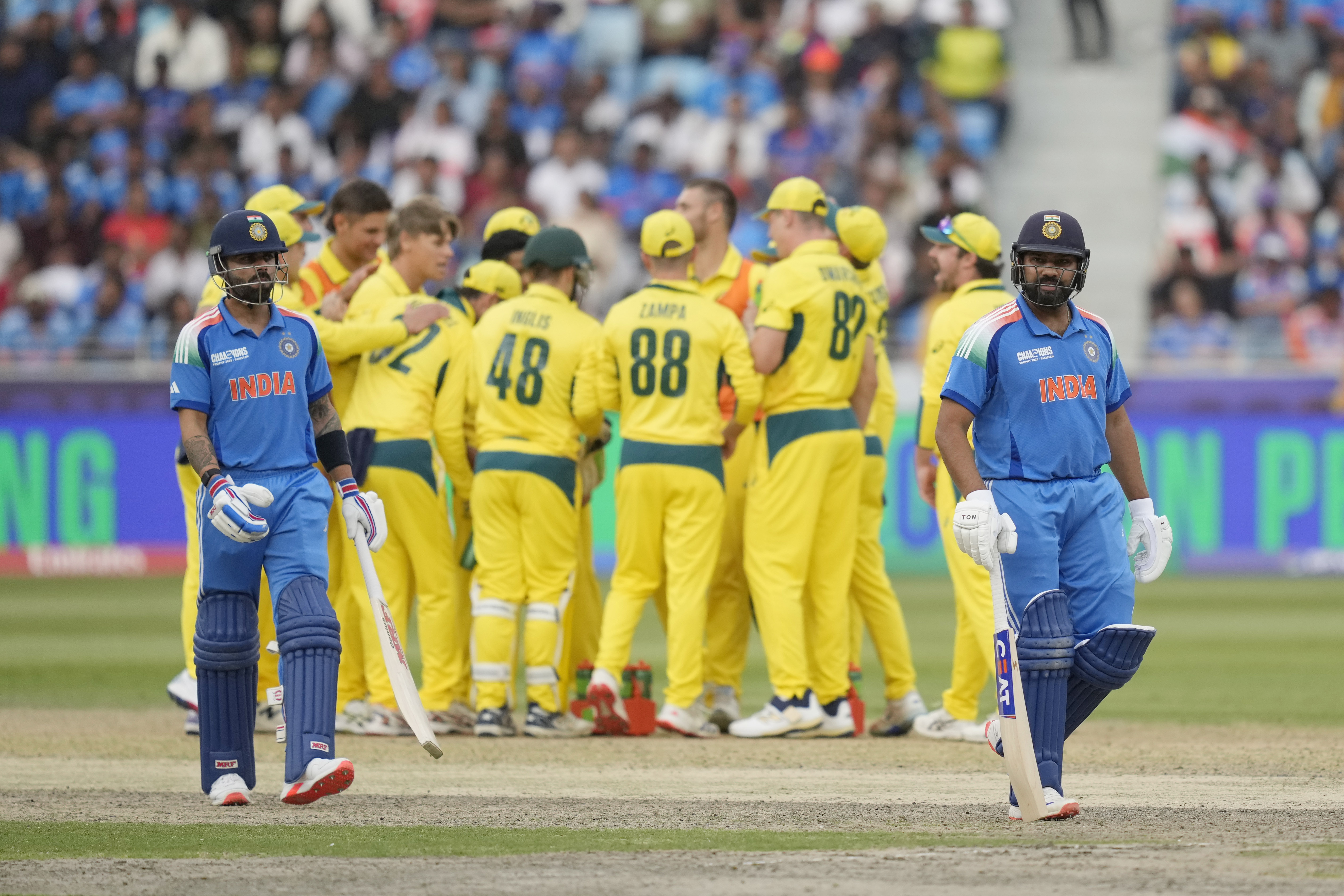 India's captain Rohit Sharma, right, walks off the field after losing his wicket as India's Virat Kohli, left, watches during the ICC Champions Trophy semifinal cricket match between India and Australia at Dubai International Cricket Stadium in Dubai, United Arab Emirates, Tuesday, March 4, 2025. (AP Photo/Altaf Qadri)