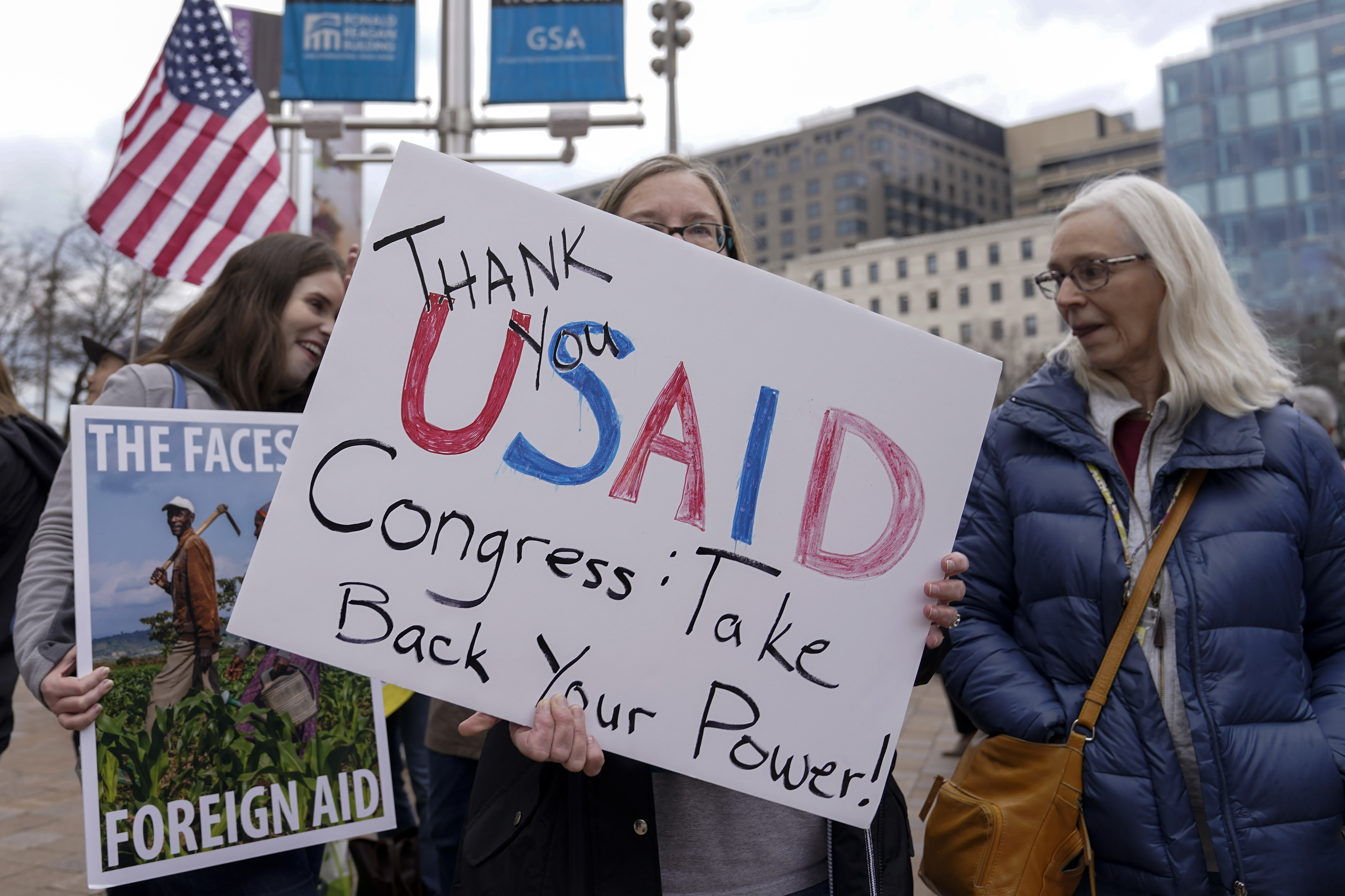 A protester holds up a sign that reads, "Thank you USAID. Congress take back your power."