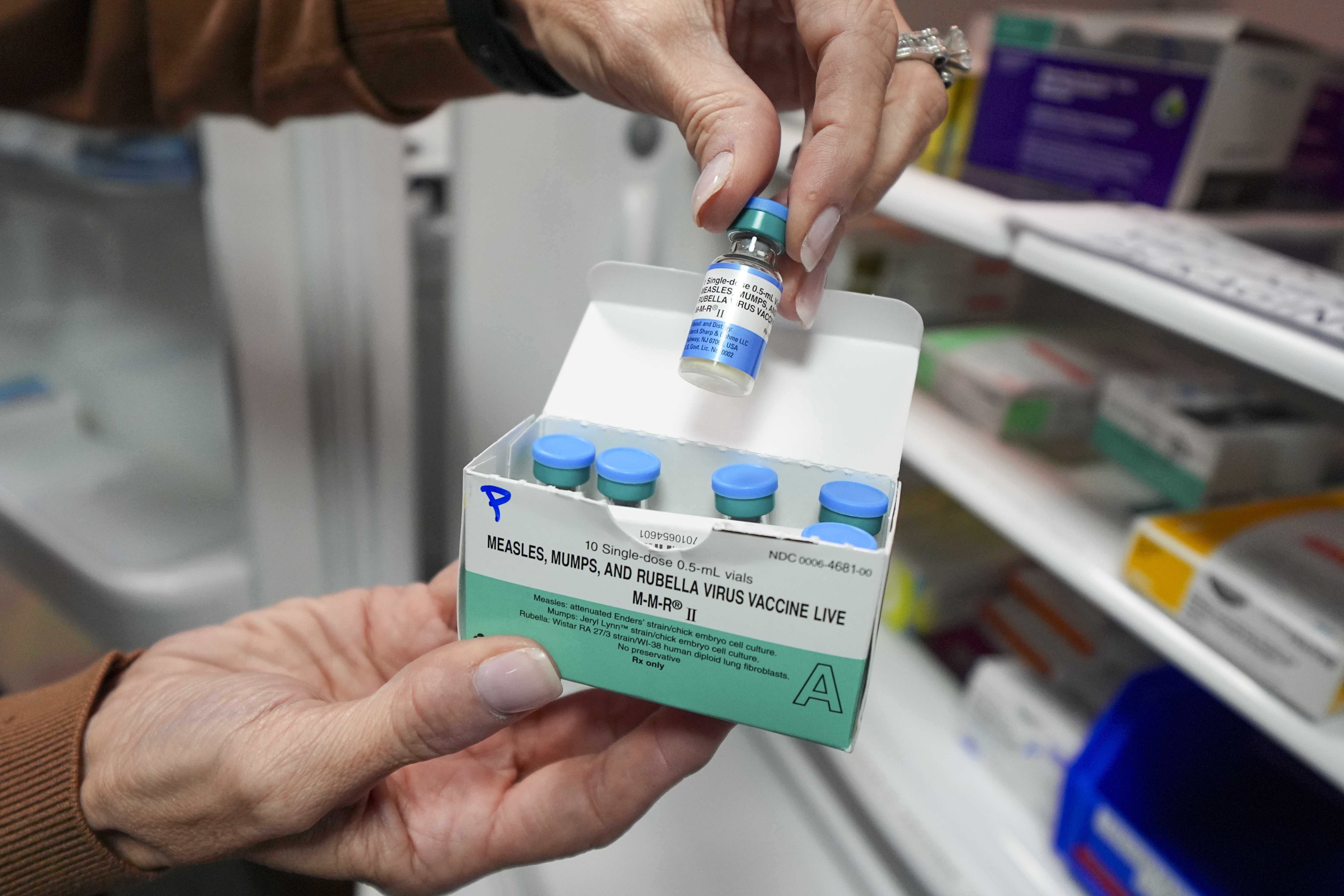 A healthcare provider lifts a vial of vaccine out of a box.