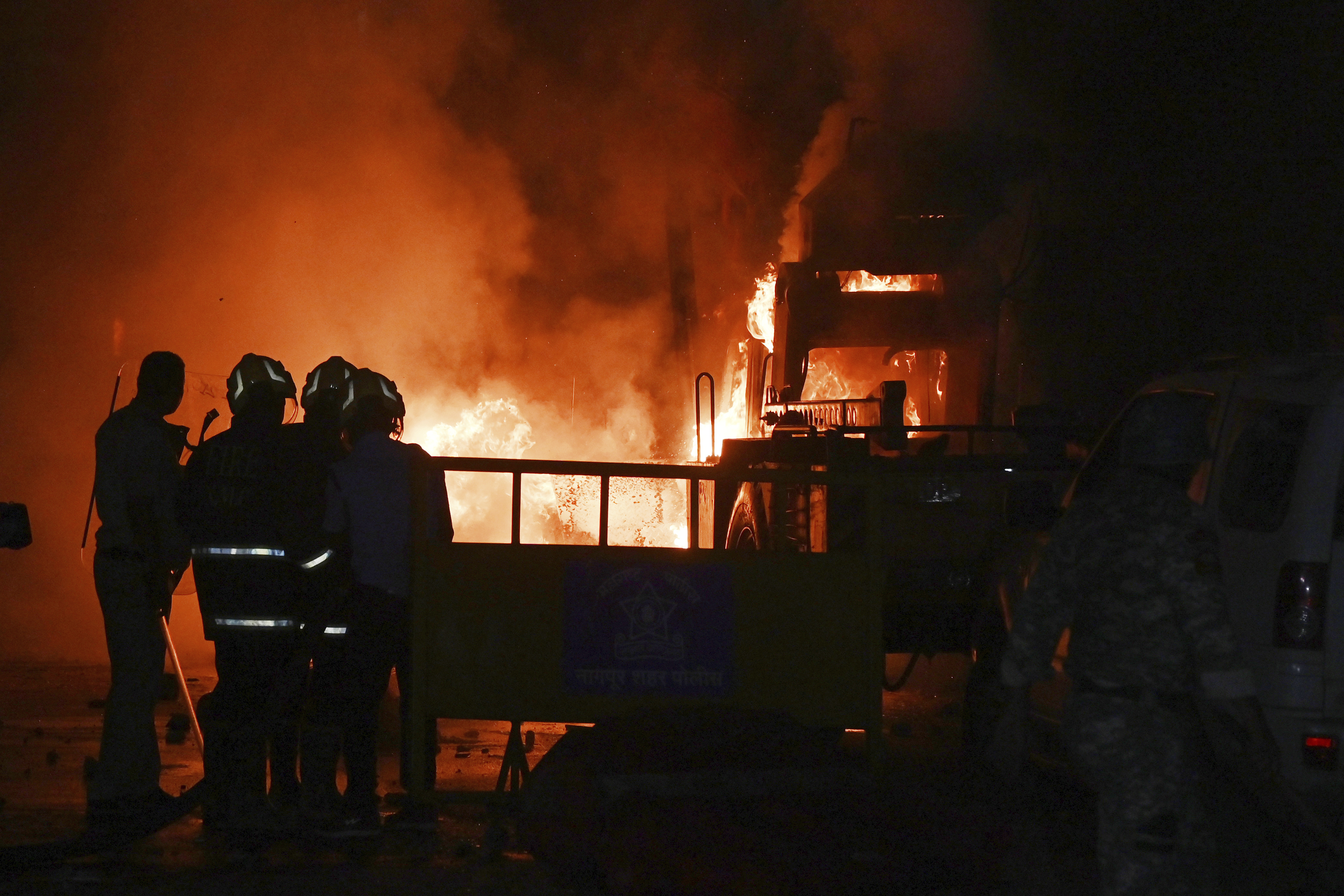 Policemen watch as vehicles are torched during communal clashes sparked by protests in Nagpur, India