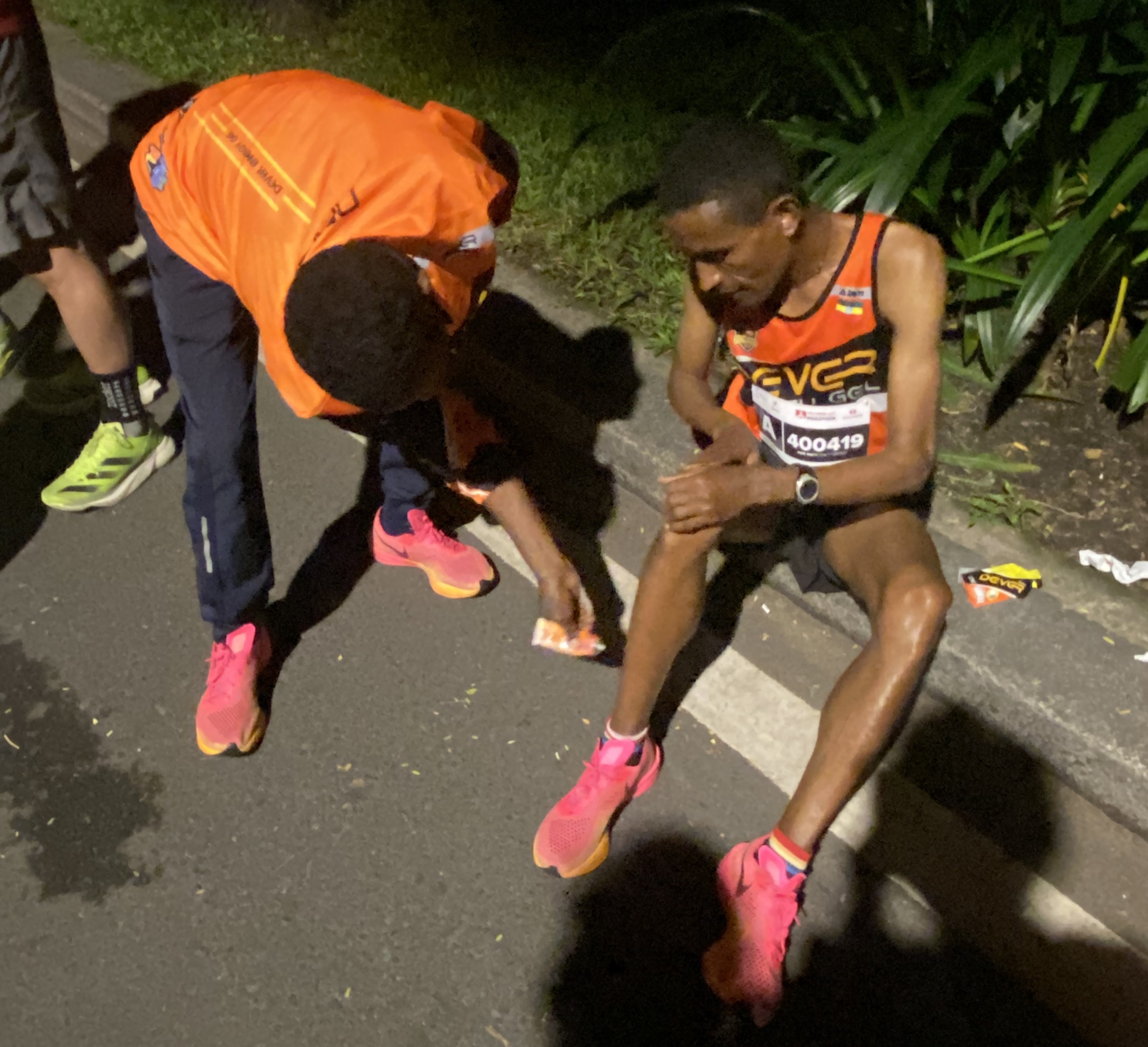 Ethiopian runner Miko applies balm to teammate Keress's leg before a race in Vietnam [Danh Nguyen]