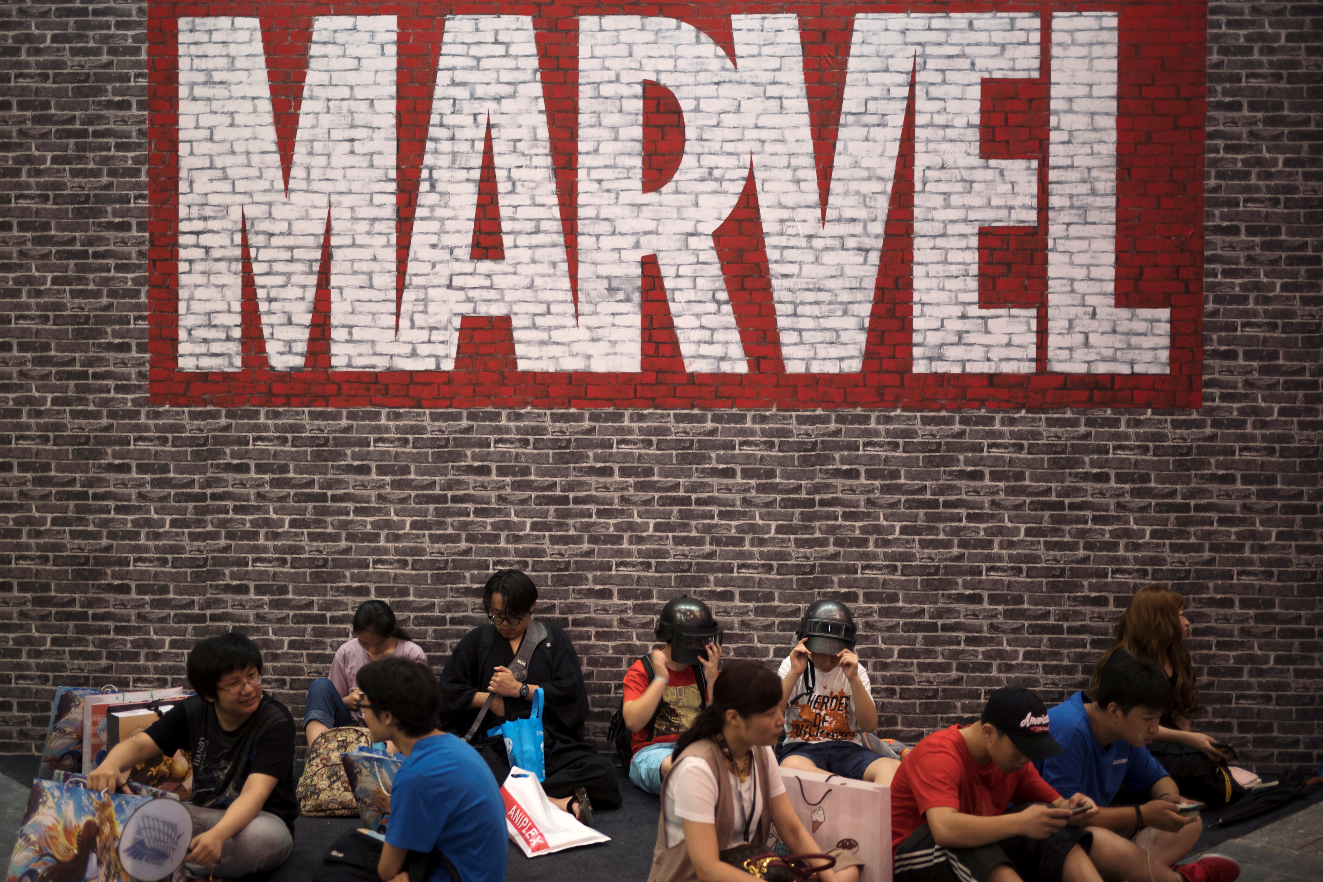 Visitors sit under a Marvel sign at the China International Cartoon and Game (CCG) Expo in Shanghai, China July 5, 2018. Picture taken July 5, 2018. REUTERS/Stringer ATTENTION EDITORS - THIS IMAGE WAS PROVIDED BY A THIRD PARTY. CHINA OUT.