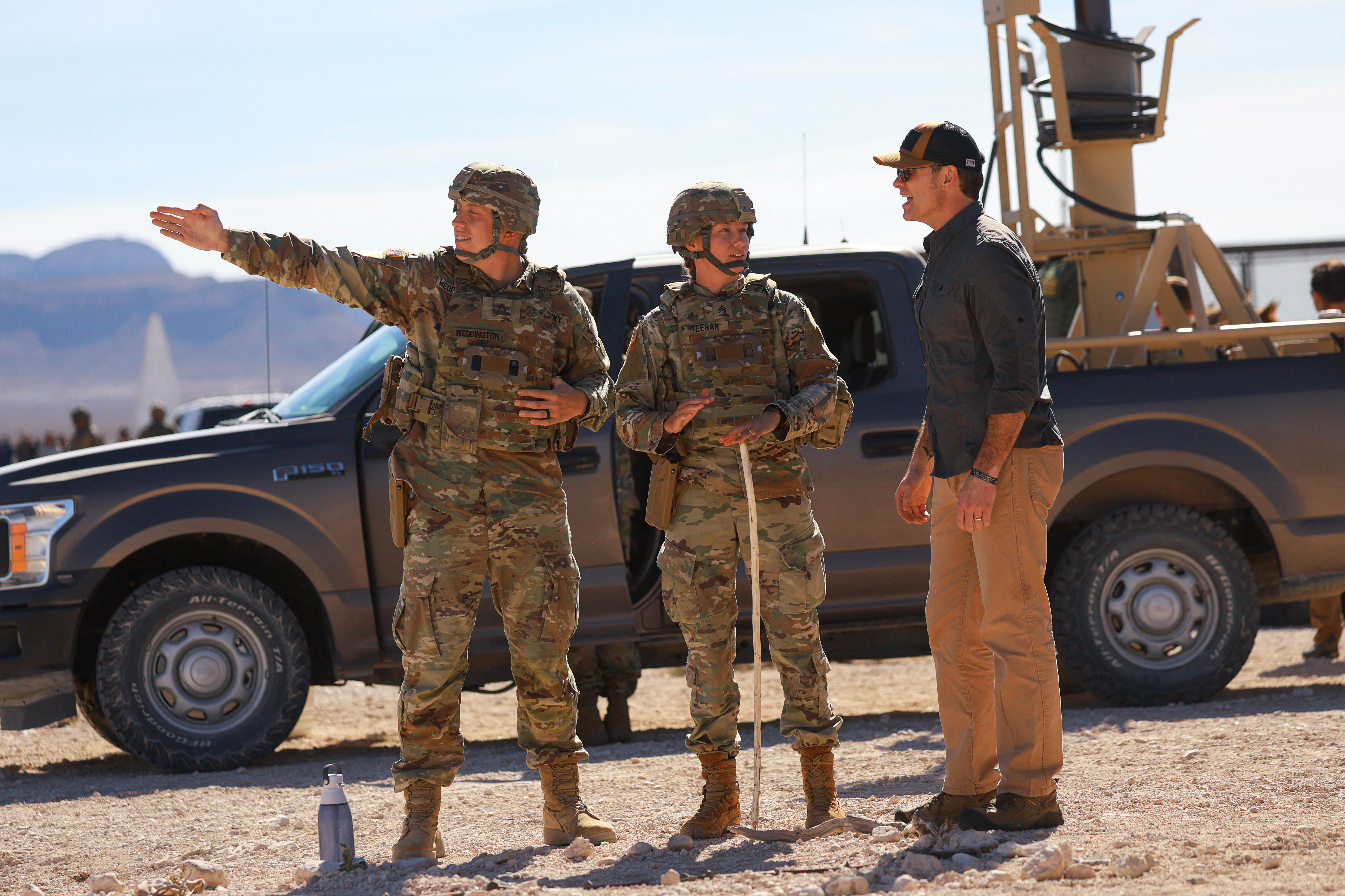 Soldiers point as they speak with Pete Hegseth at the US-Mexico border.