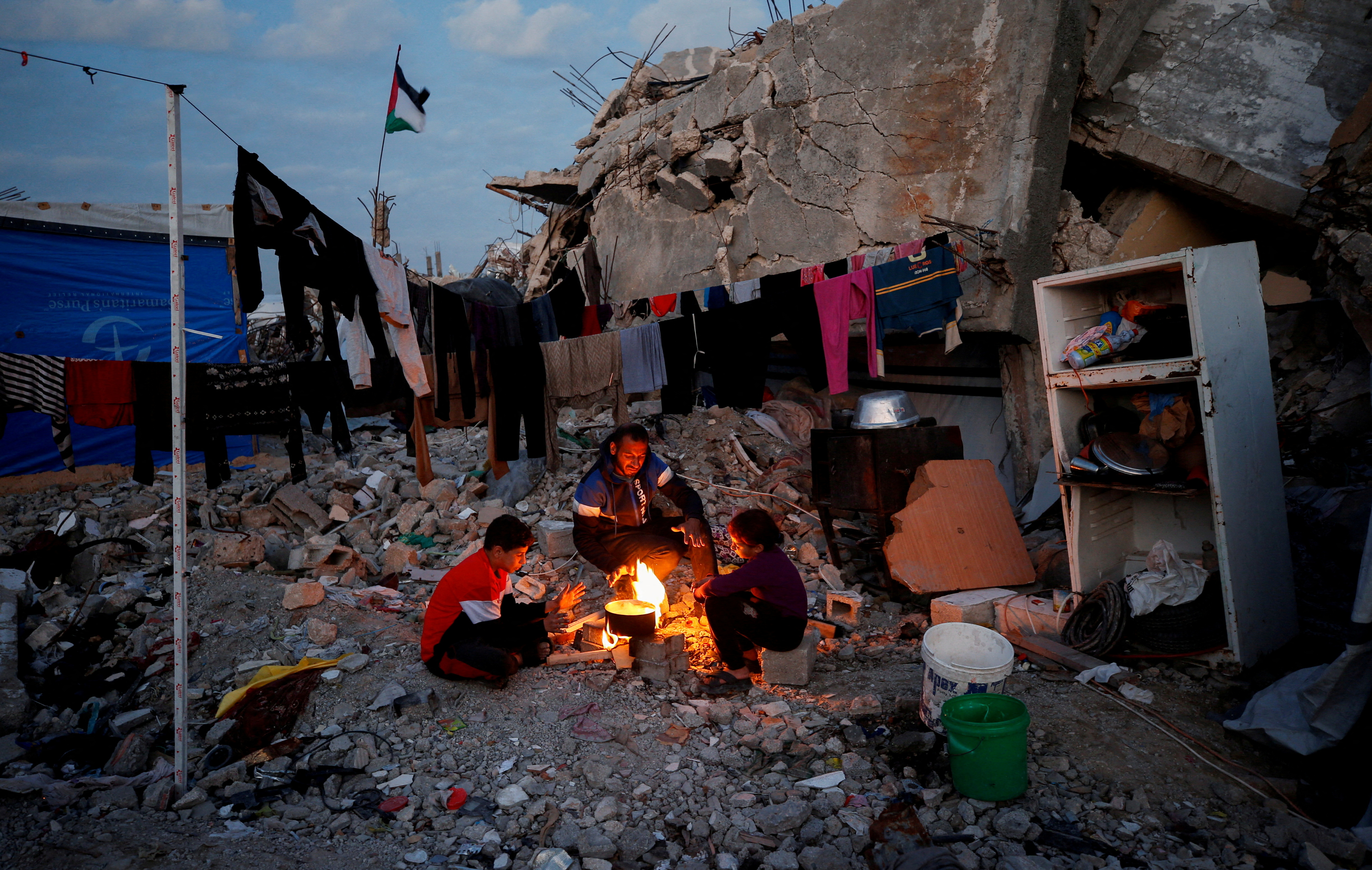 Palestinians sit around a fire among the rubble of buildings destroyed during the Israeli offensive, amid a ceasefire between Israel and Hamas, at Jabalia refugee camp, northern Gaza Strip, February 17, 2025. REUTERS/Mahmoud Issa TPX IMAGES OF THE DAY REFILE - CORRECTING FROM "AMONG RUBBLE OF DESTROYED BUILDINGS DURING THE ISRAELI OFFENSIVE" TO "AMONG THE RUBBLE OF BUILDINGS DESTROYED DURING THE ISRAELI OFFENSIVE".